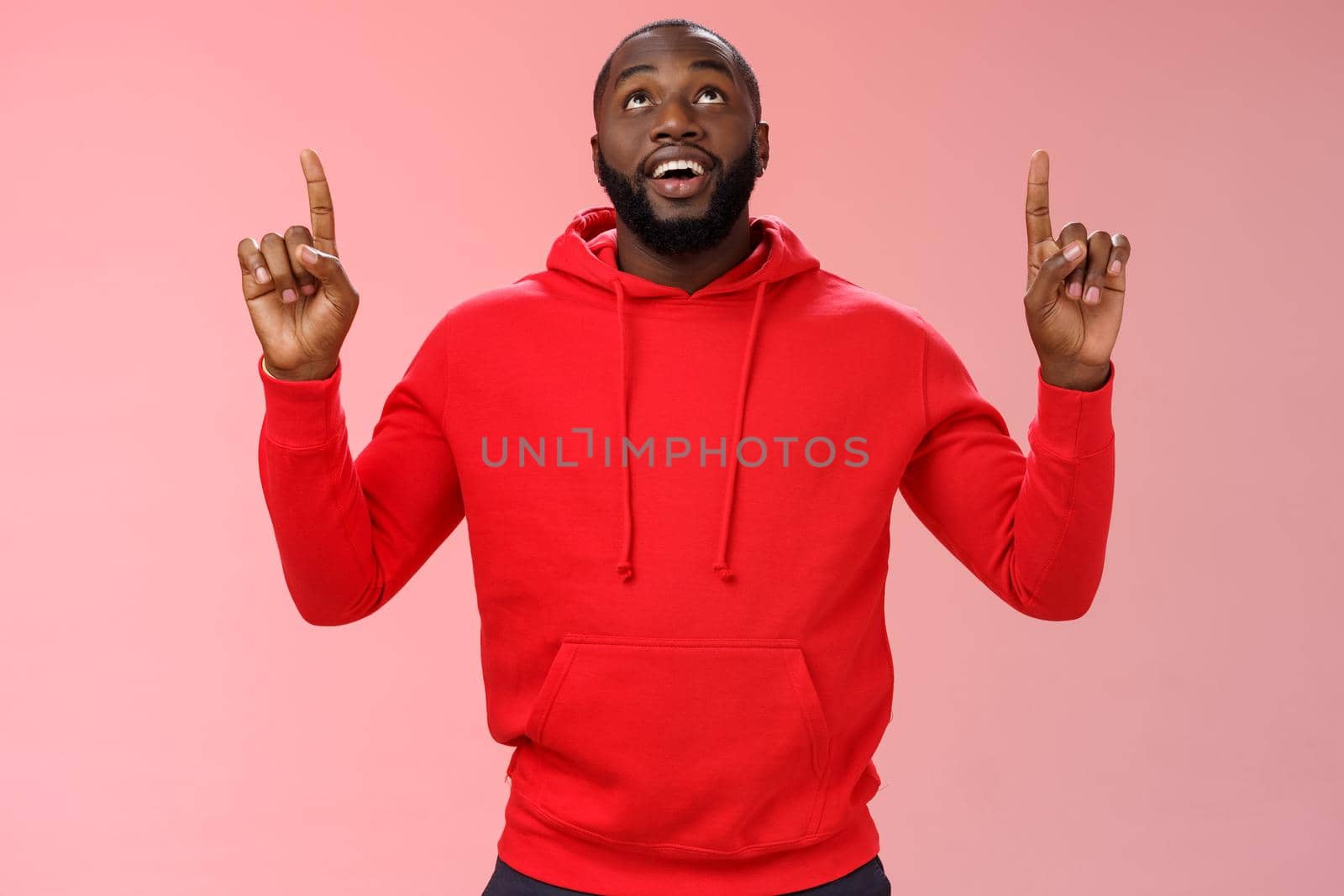Fascinated attractive black bearded boyfriend gazing shooting star raise head impressed smiling amused pointing up curiously looking upwards, standing pink background enjoy stargazing.