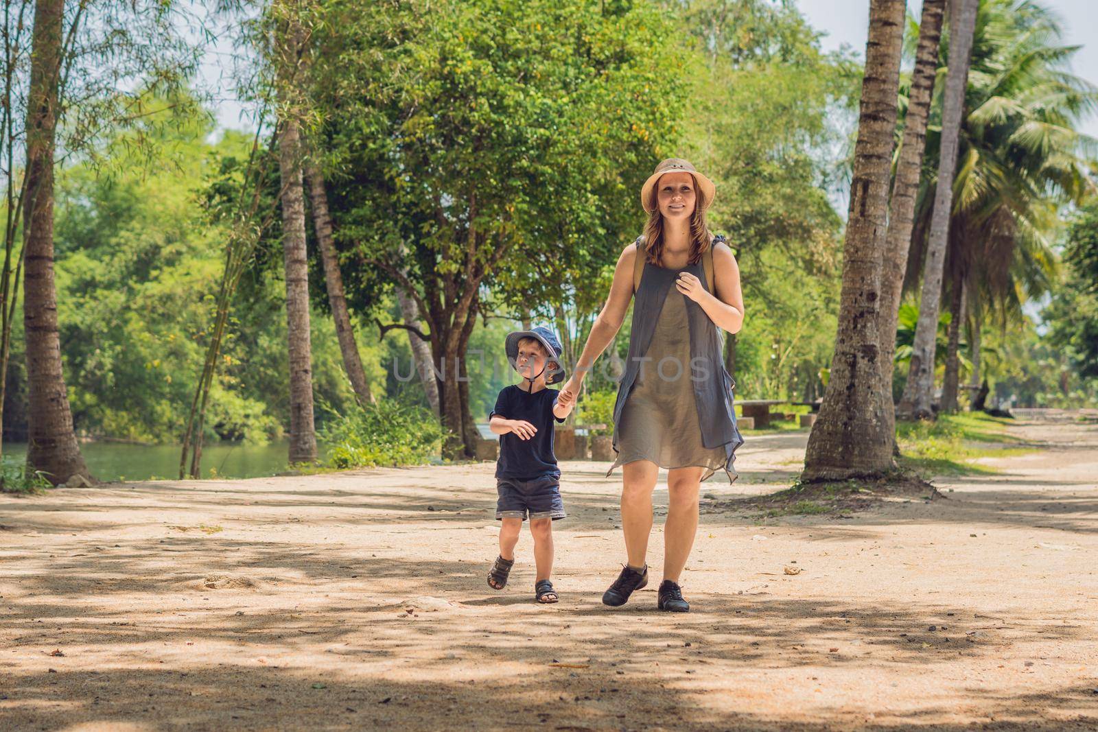 Mom and son are walking on the forest road.