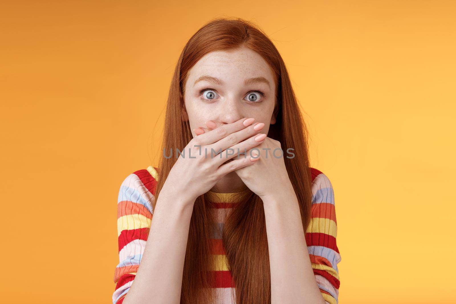Oops sorry. Girl feeling awkward saying inappropriate word standing unconfident cover mouth palms wide eyes staring camera shocked express surprise nervously standing orange background by Benzoix