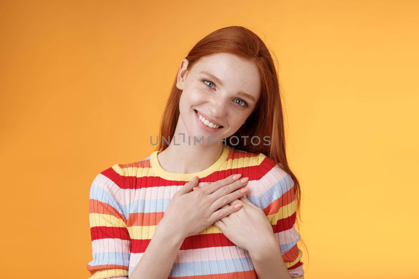 Pleased tender feminine good-looking redhead woman receive compliment confession touch heart feel warmth dearest moment smiling delighted lovely keep love inside soul, standing orange background.