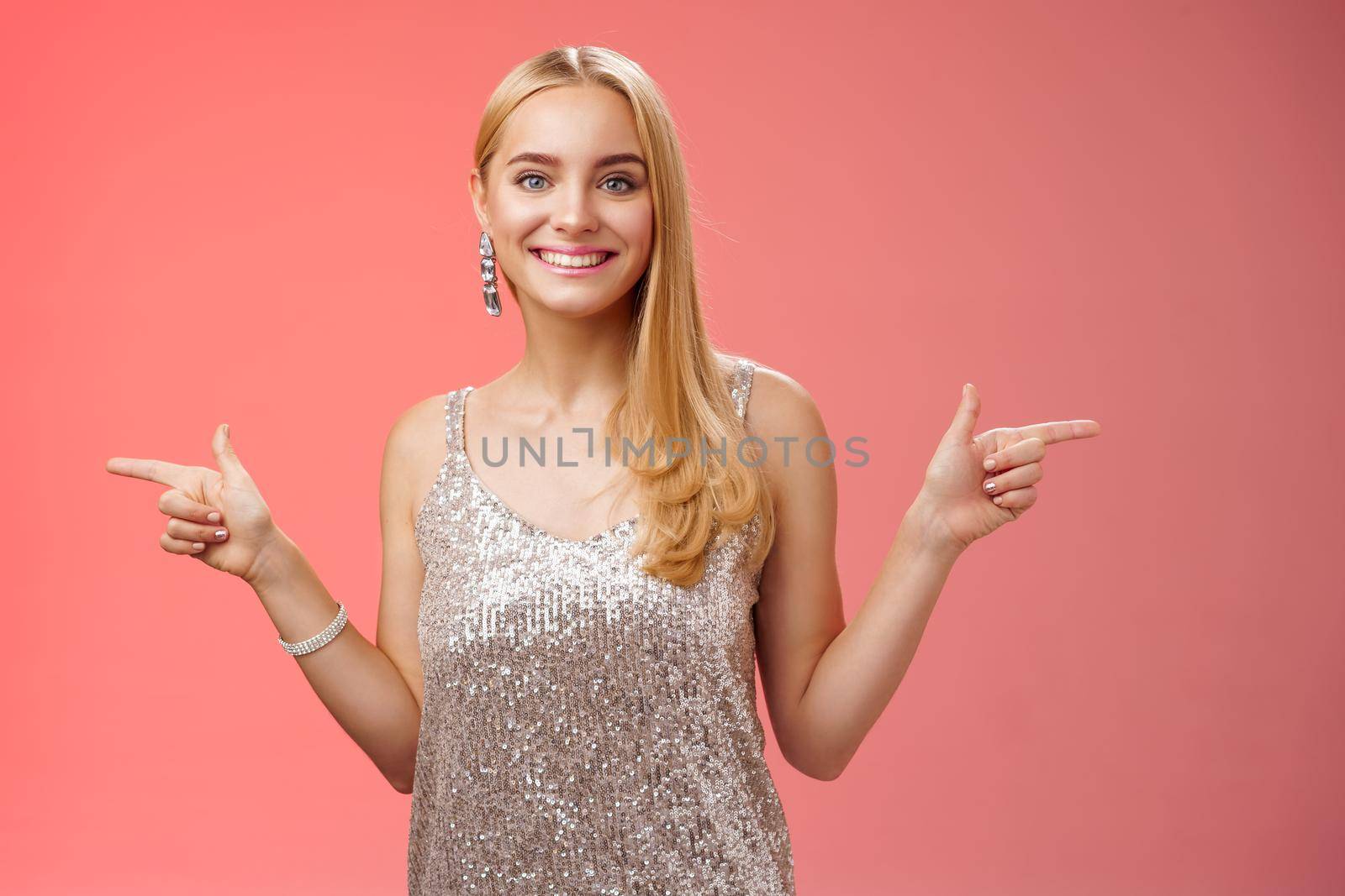 Waist-up shot energized cheerful blond european girl in silver glittering dress pointing sideways left right smiling amused showing lots variants variety opportunities make choice which better by Benzoix