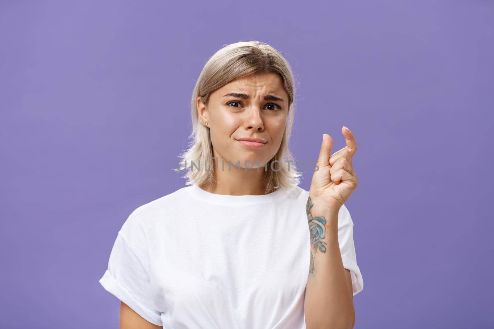 Woman feeling regret lacking small amount of money to afford car. Unhappy displeased good-looking stylish female with tattoos on hands frowning and pursing lips shaping tiny or little object by Benzoix