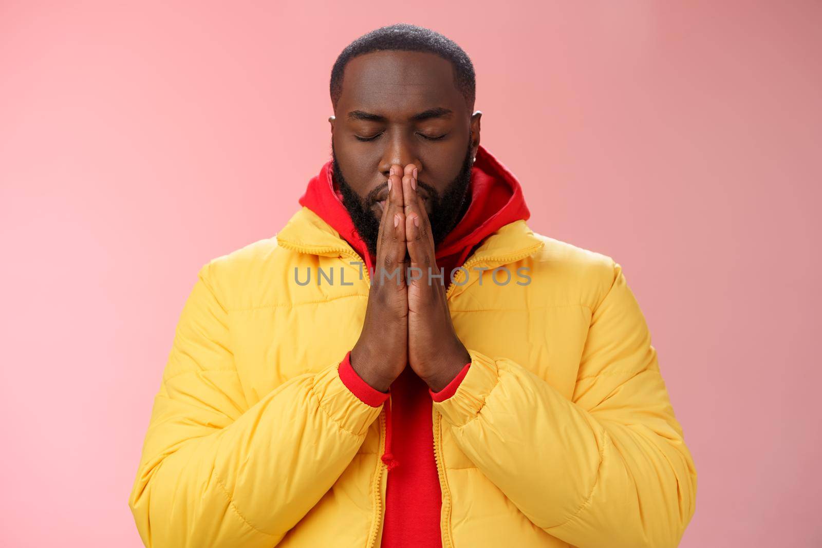 Serious-looking determined young focused african-american man prepare will important meeting press palms together hands pray close eyes supplicating praying make wish, standing pink background.