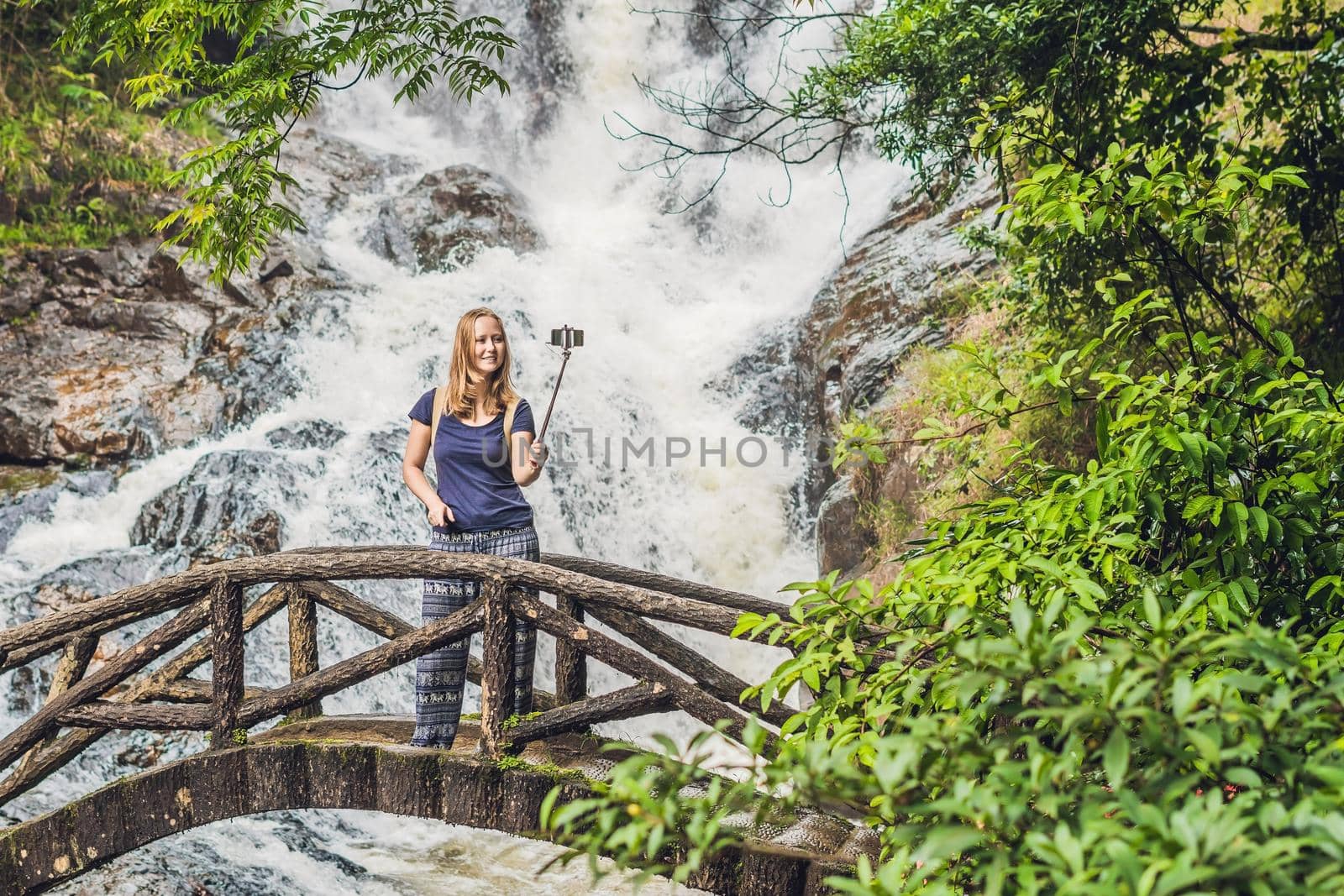 Excited female tourist making self portrait in front of the waterfall. Woman having a great vacation in Vietnam.