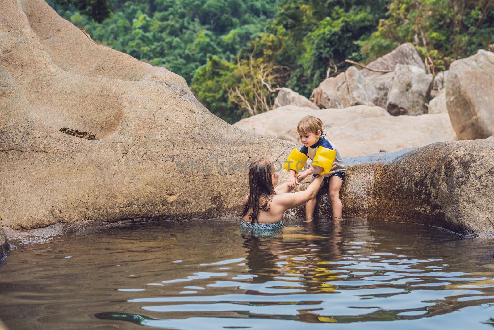 Mom and young son on a background of stones and a river. Traveling with kids concept by galitskaya