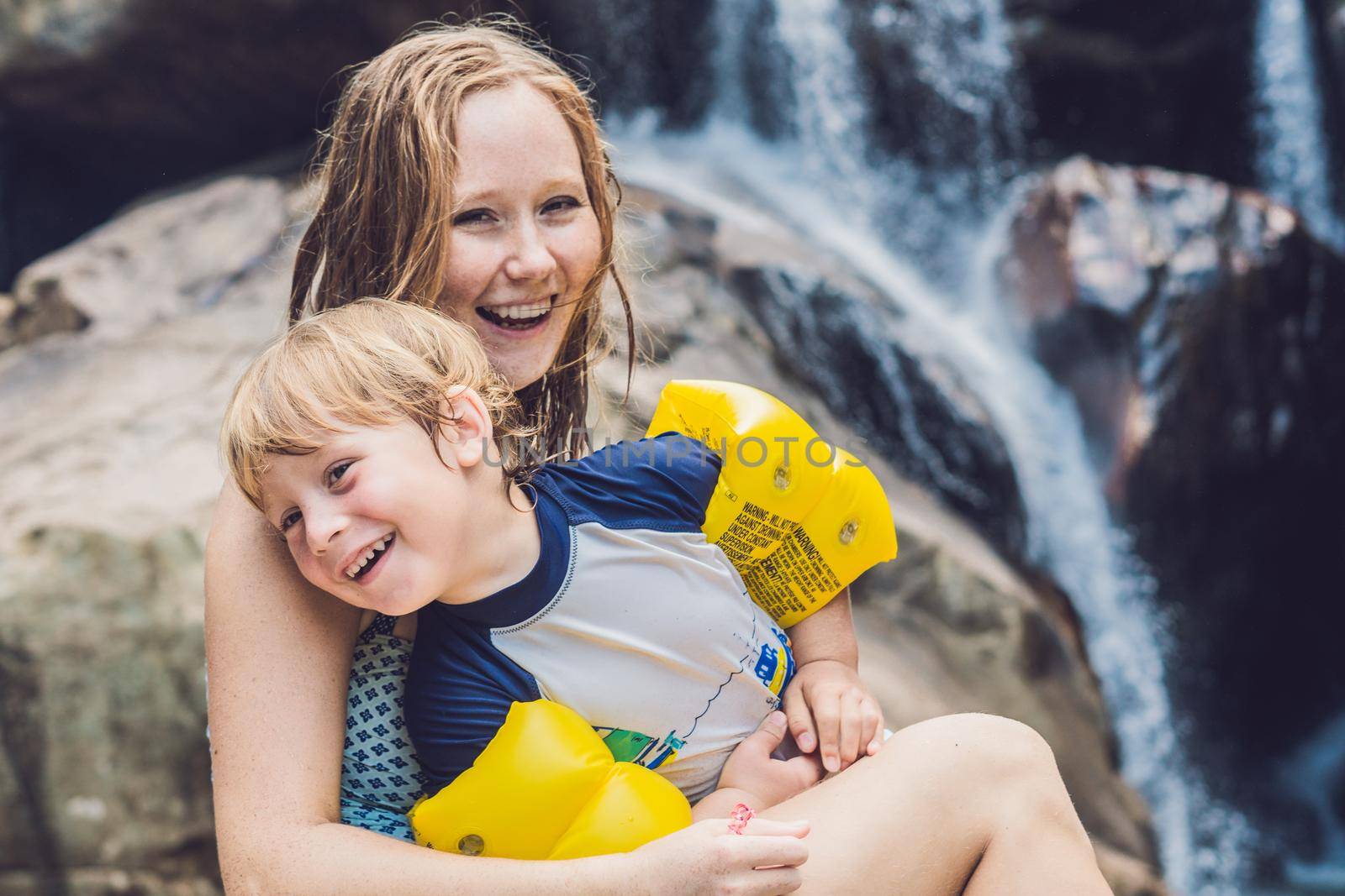 Mom and young son on the waterfall background. Traveling with kids concept.