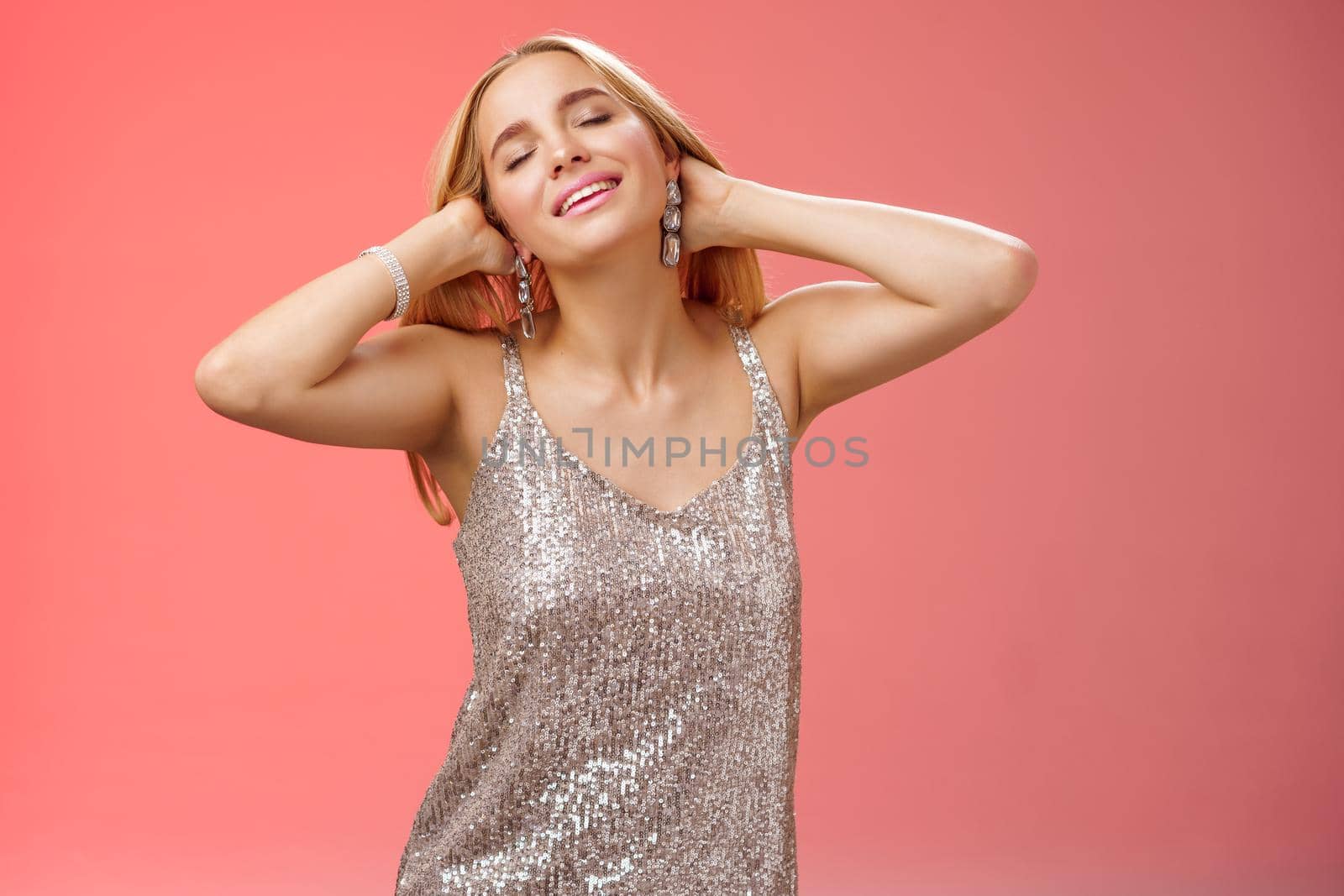 Carefree relaxed feminine lovely blond woman in silver dress enjoying slow music dance-floor run hands through hair feel free relieved joyful close eyes raise head enjoying chilling vibe by Benzoix