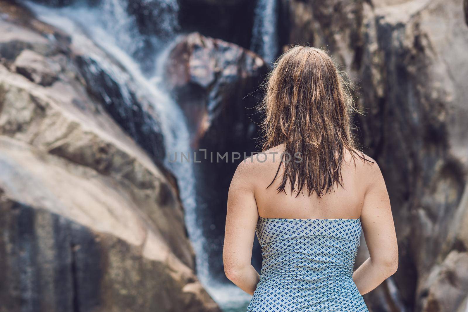 Young woman sits on a waterfall background.
