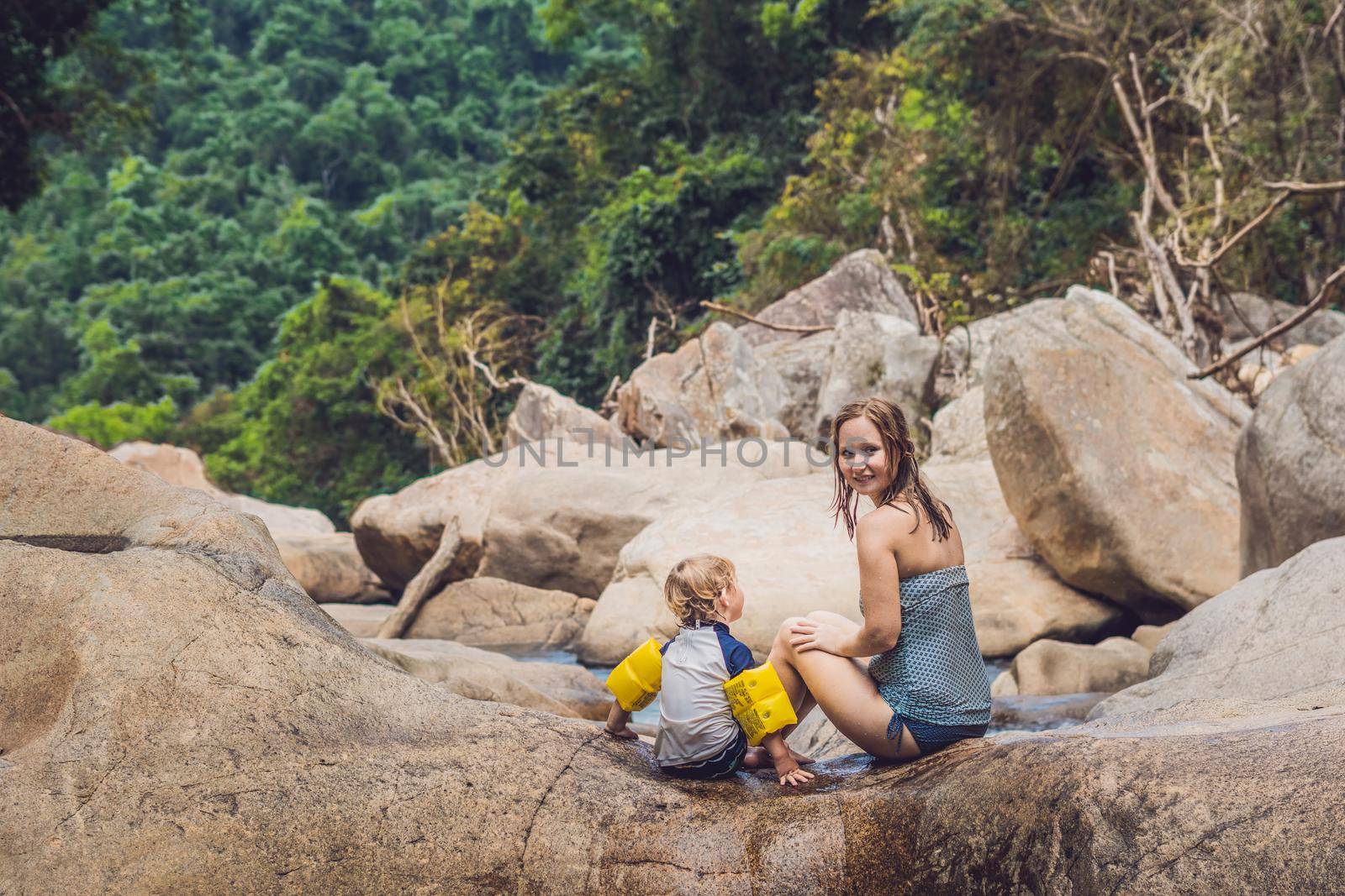 Mom and young son on a background of stones and a river. Traveling with kids concept.