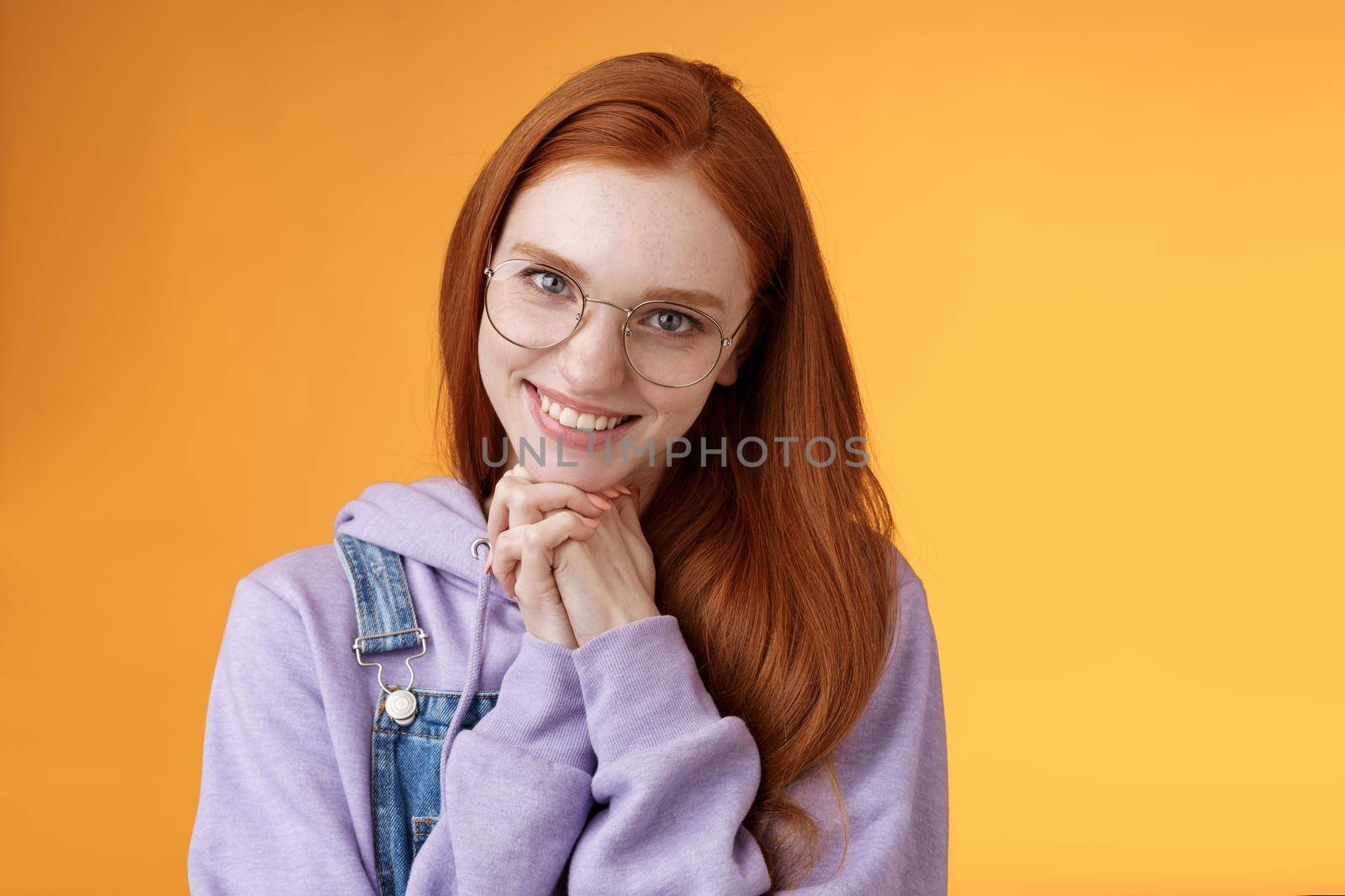 Flirty young clingy girlfriend redhead girl trying learn flirt making creepy lovely smile lean head palms seducing guy standing orange background glancing romantically wear glasses. Copy space