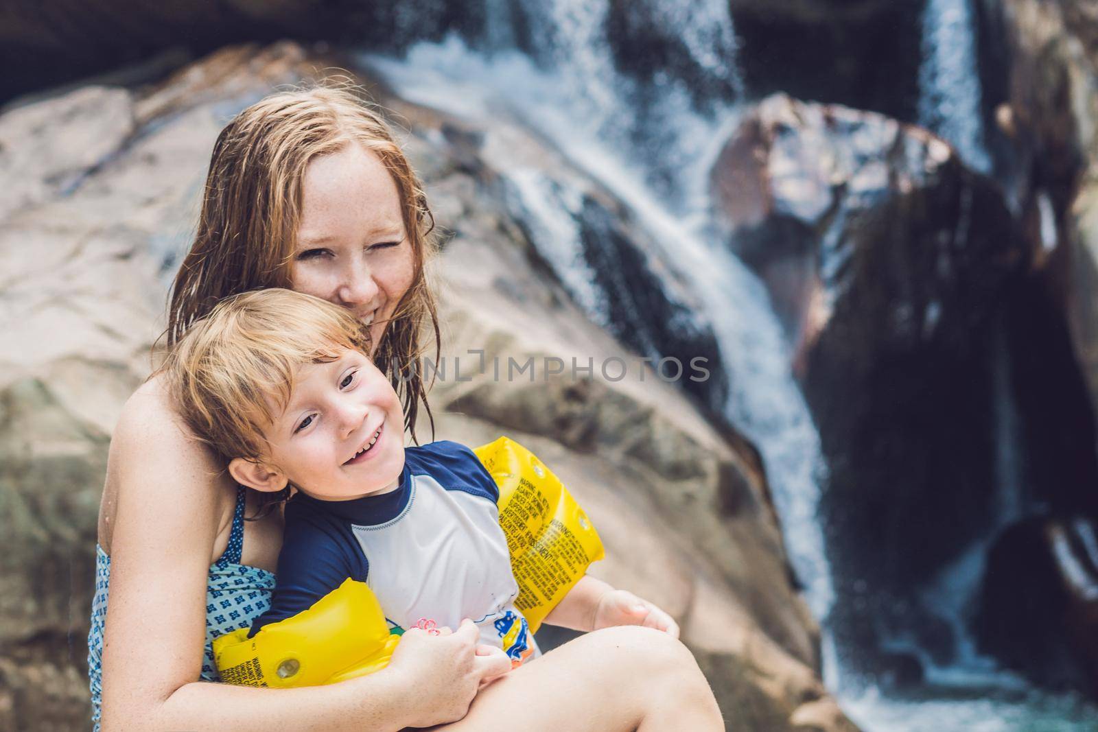 Mom and young son on the waterfall background. Traveling with kids concept by galitskaya