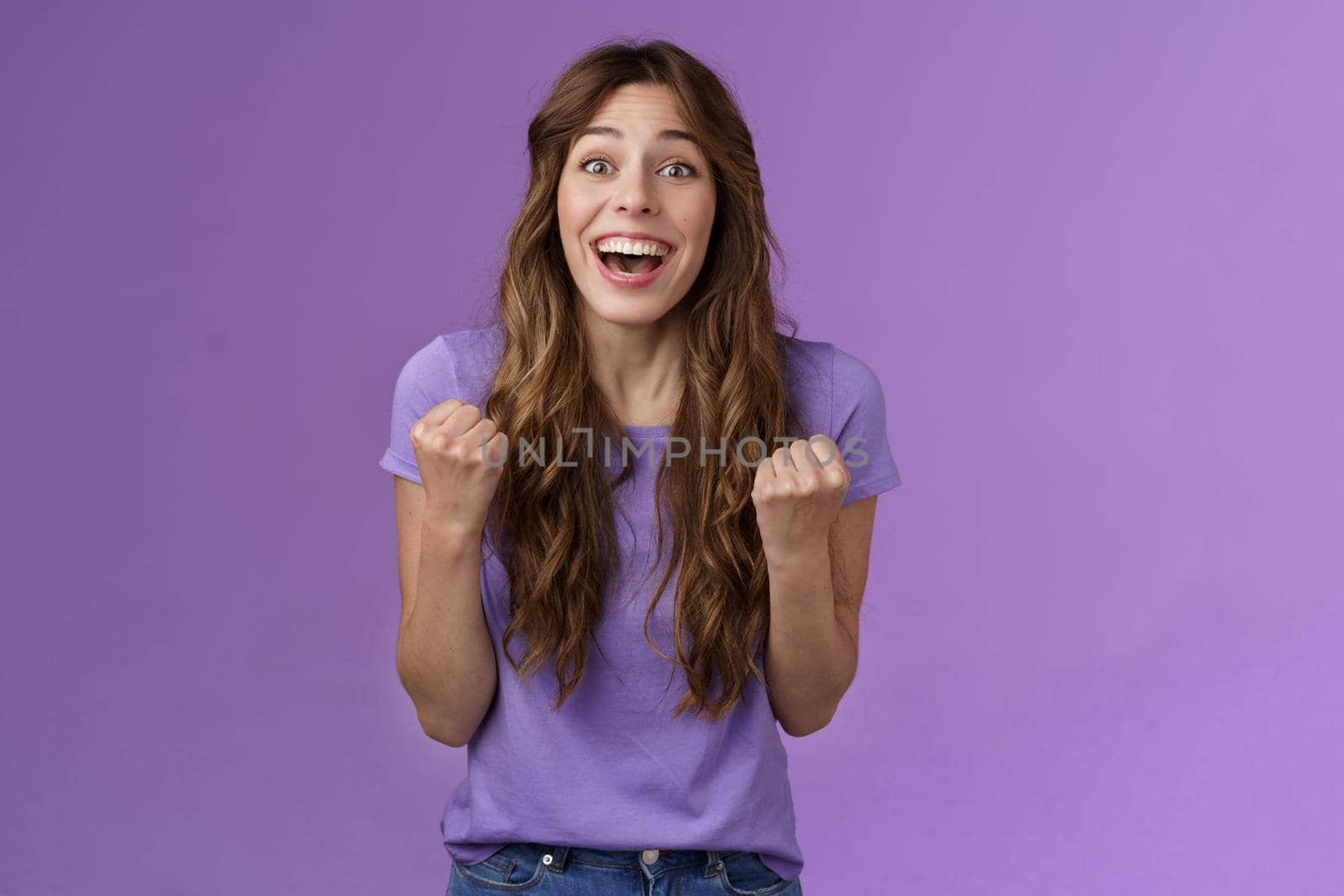 Cheerful cute devoted curly girl smiling broadly rooting for friend fist pump grinning admiration fan watching game favorite team wanna win see success celebrating triumphing joyfully by Benzoix