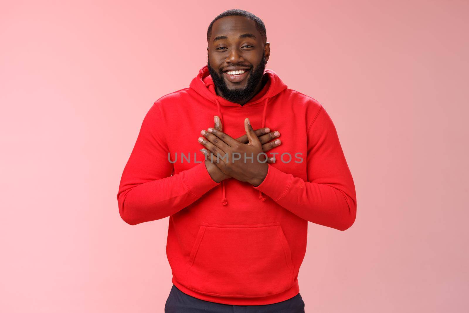 Pleased touched african american smiling young bearded man hold hands heart grinning thanking heartwarming lovely congratulations, receive good feedback standing happy thanking everyone.