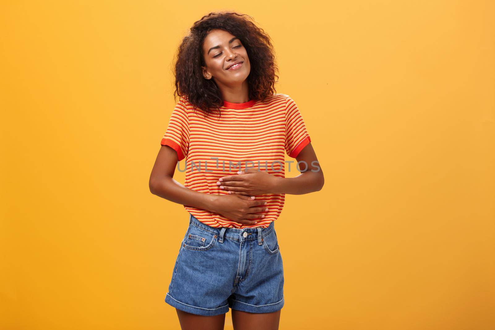 Mmm delicious meal warming me inside. Delighted stuffed good-looking stylish young female in striped t-shirt rubbing belly with satisfaction closing eyes from pleasure after eating tasty food. Restaurants and people feelings concept