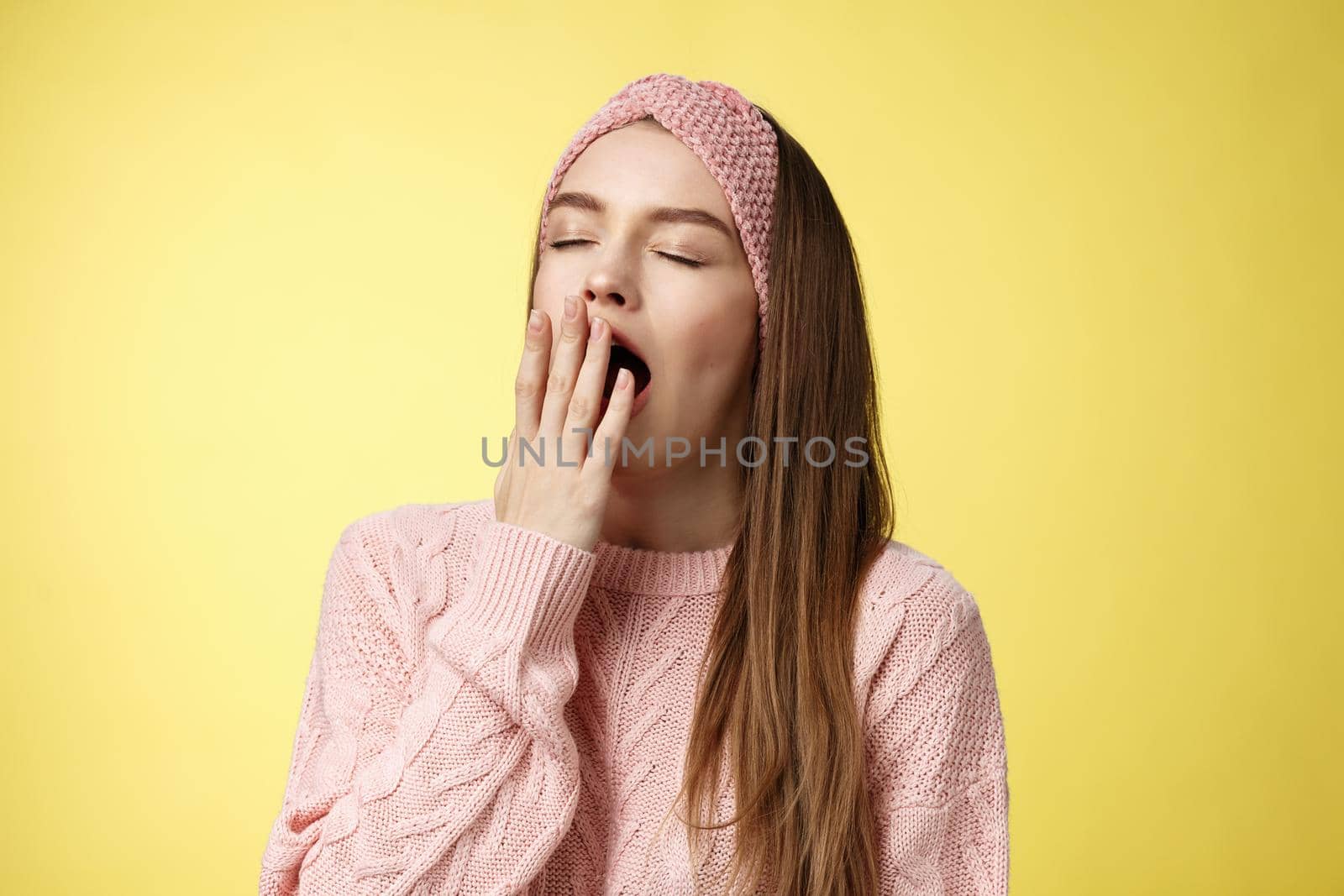 Time to bed. Portrait of tired cute sleepy girlfriend wearing sweater, knitted headband yawning cute with closed eyes opened mouth covered with palm, exhausted, wanting sleep, dreaming fall asleep.