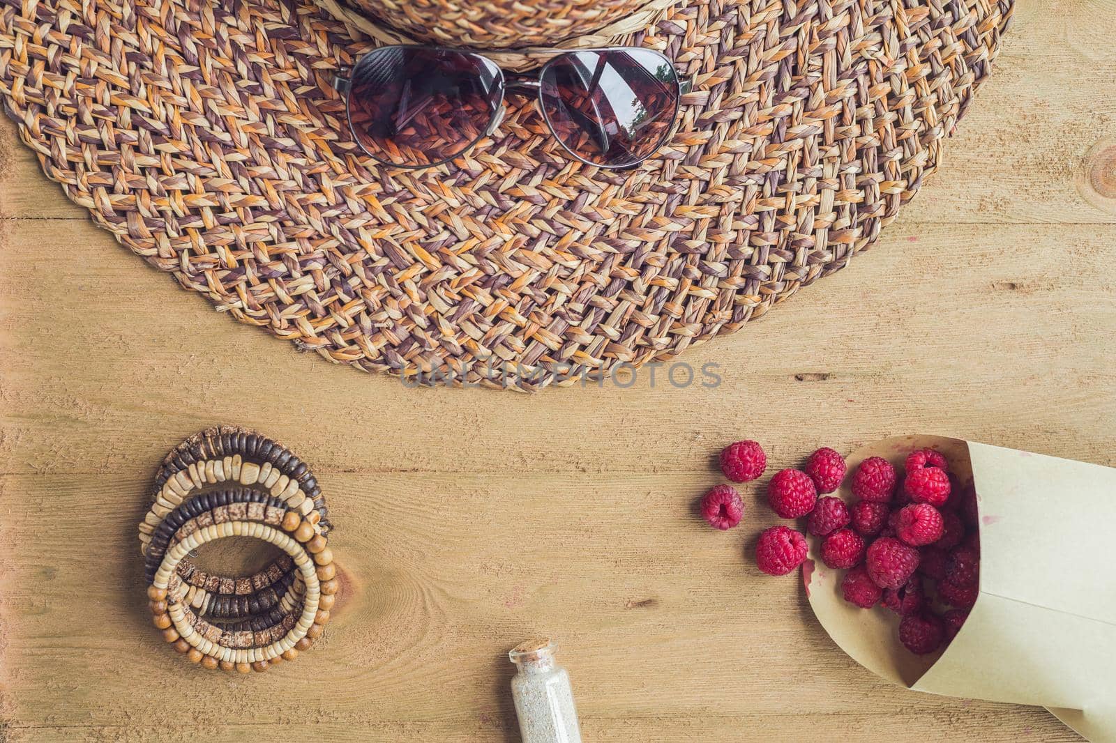 Summer holiday, vacation, relaxation concept. Raspberries, straw hat, mobile phone, smartphone, headphones, sunglasses from above, top view, flat lay on wooden background. Colorful background with free text copy space. Summer vibes concept.