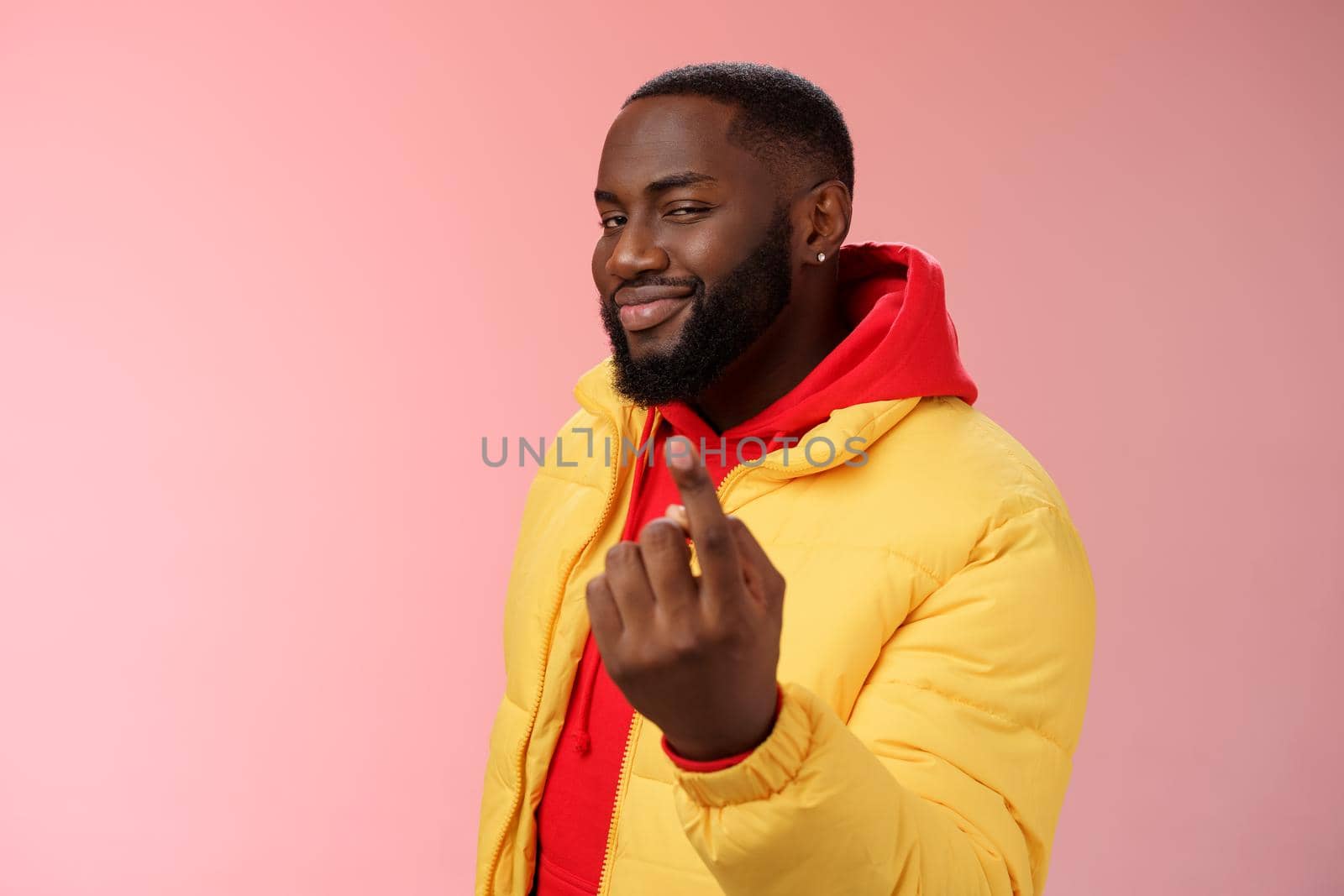 Cheeky flirty black bearded guy asking come closer beckon index finger camera smiling make smug face have plans for you alluring join, standing pink background devious grin. Emotions concept