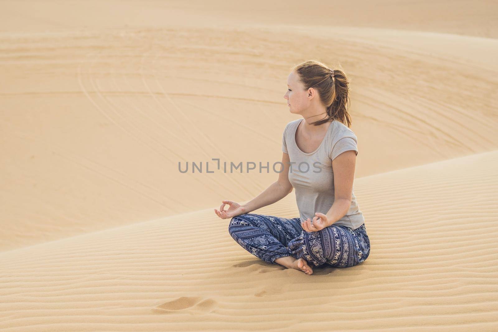 Young woman meditating in the desert by galitskaya