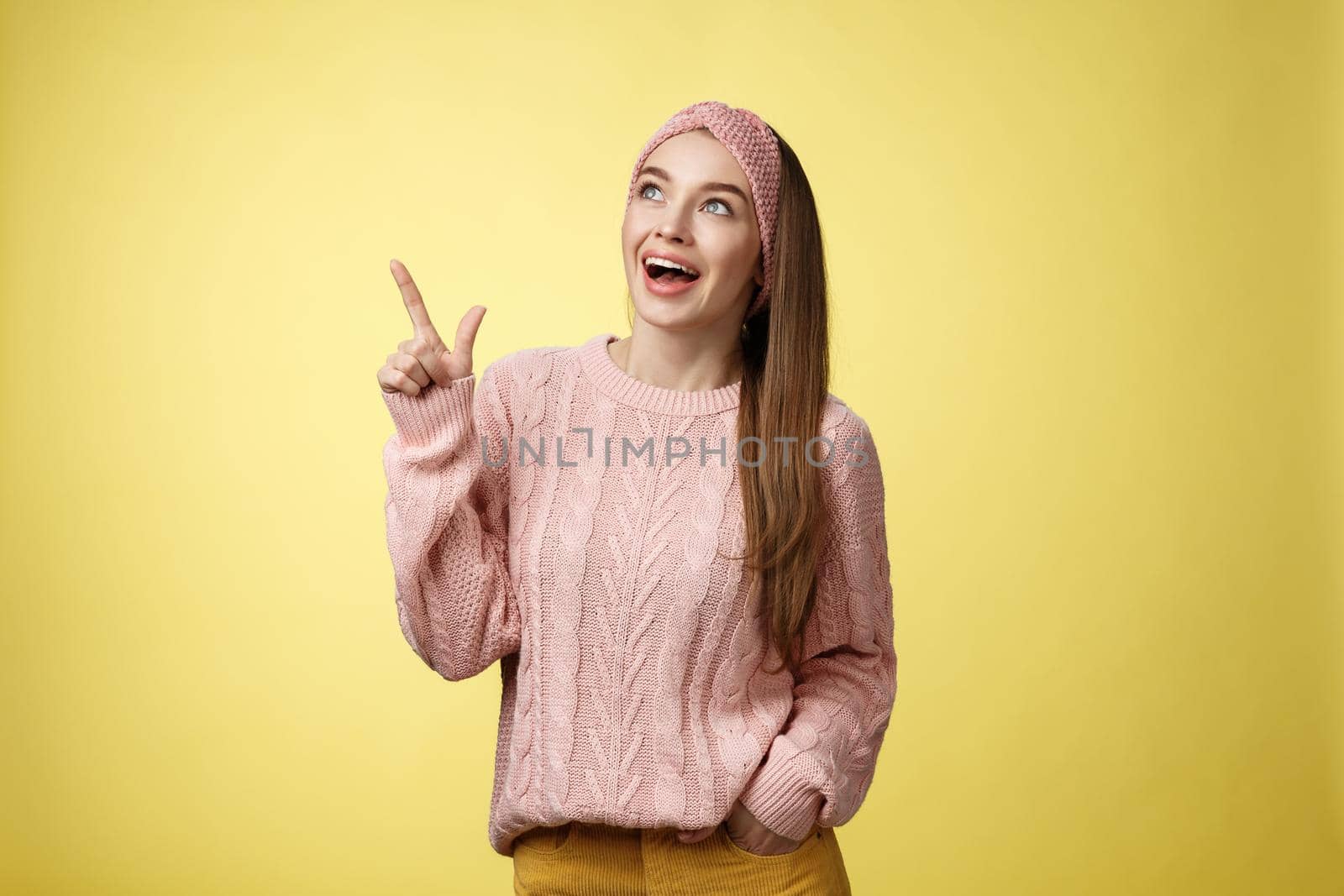 Amused and impressed dreamy pretty young european woman in knitted sweater gasping entertained dropping jaw smiling thrilled, joyful, pointing, looking at upper left corner excited of awesome promo.