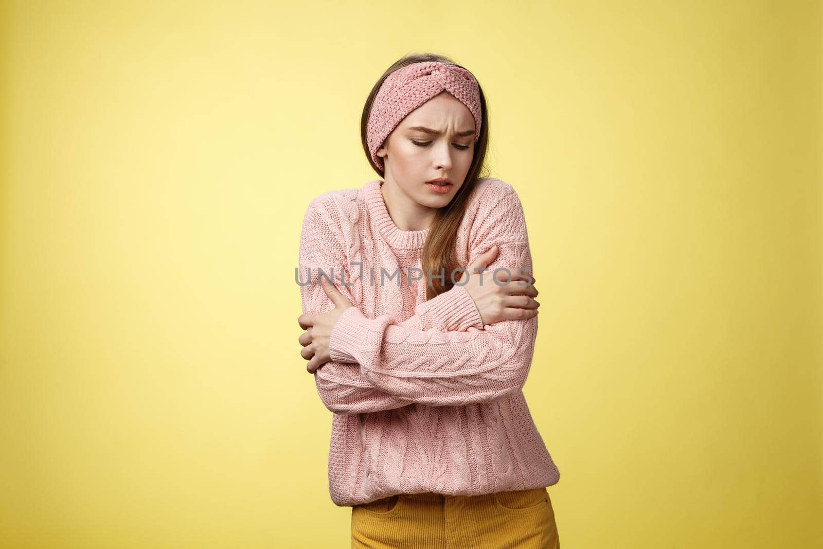 Brr girl freezing, turn-on heater. Portrait of timid cute woman wearing knitted sweater trembling from cold, embracing herself on arms looking down, stooping from discomfort cool temprature.