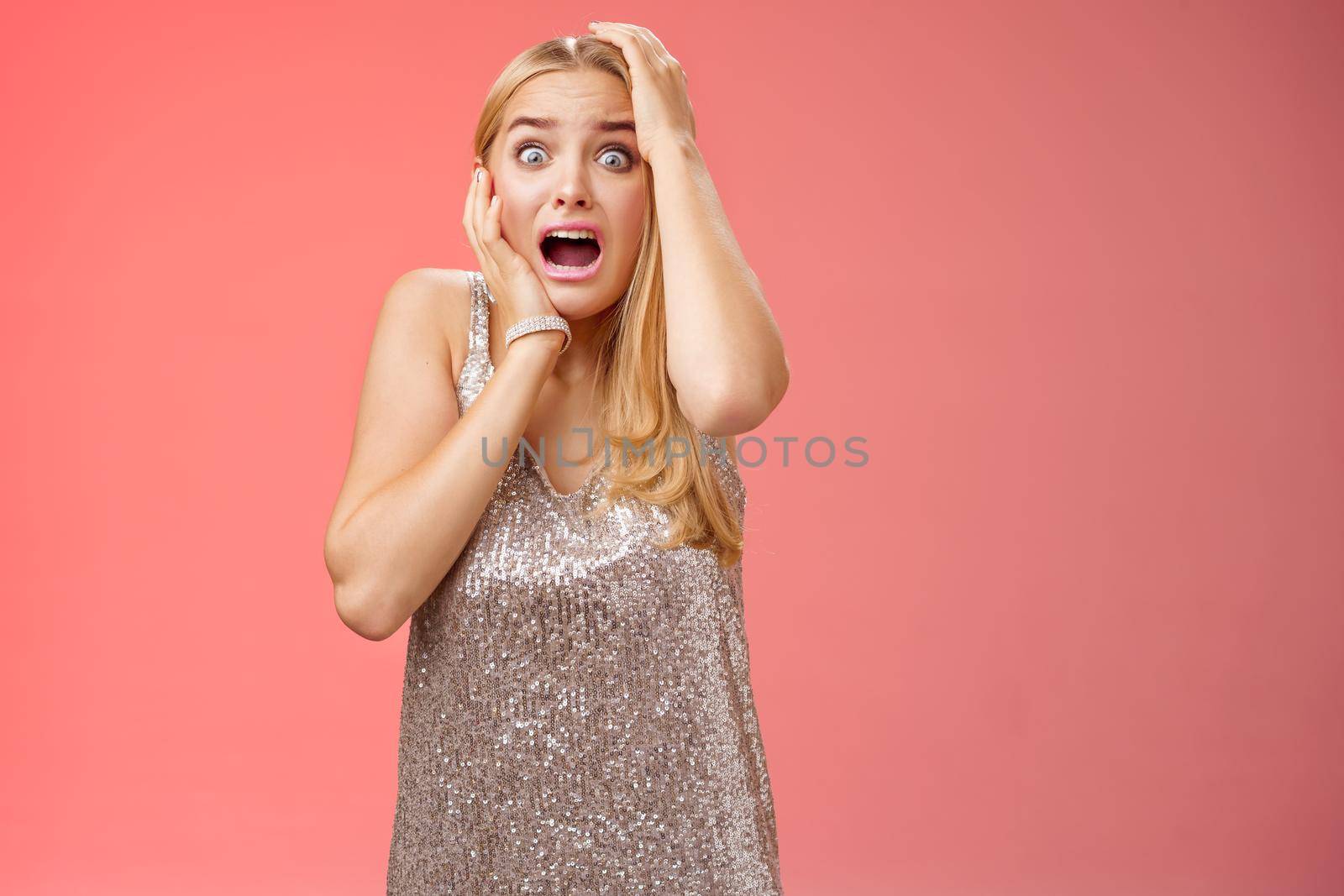 Shocked terrified blond woman horrified see crime screaming pop eyes shouting hold hands head afraid trembling fear standing frightened drop jaw gasping face terrible accident, red background by Benzoix
