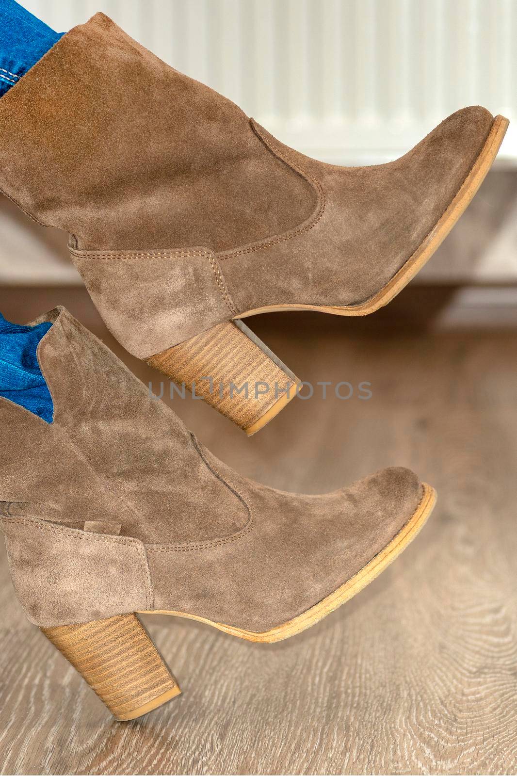 close-up. Women's suede boots. Women's brown shoes. Warm boots are put on legs at the girl. Shoe fitting.Concept of buying, trying on shoes and boots.