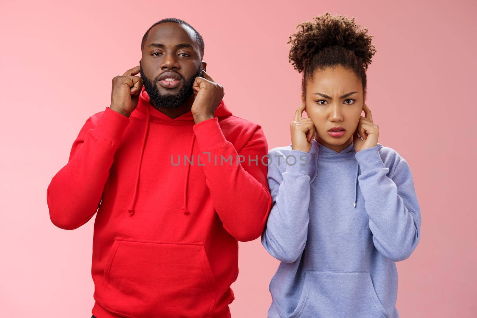 Annoyed tired couple african american woman man relationship exhausted each other close ears plug index fingers frowning look irritated hear terrible disturbing noise, standing pink background.