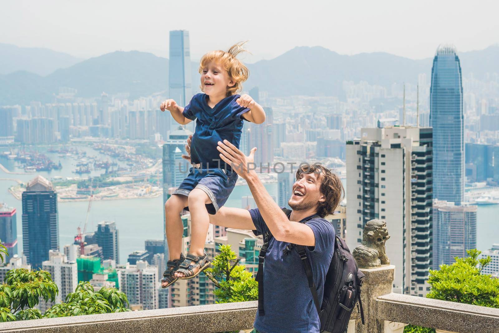 Father and son travelers at the peak of Victoria against the backdrop of Hong Kong. Traveling with children concept.