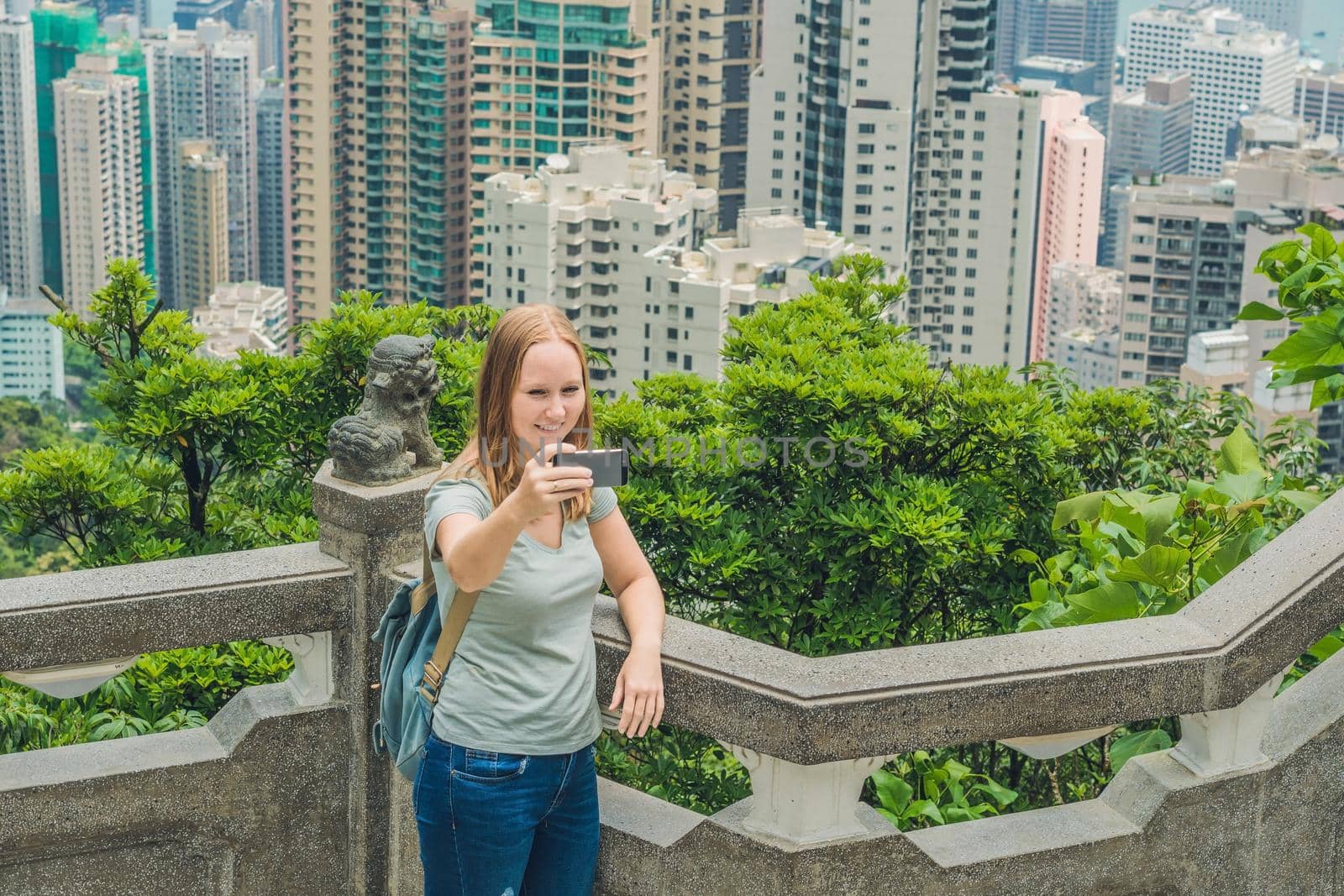 Hong Kong Victoria Peak woman taking selfie stick picture photo with smartphone enjoying view over Victoria Harbour. Viewing platform on top of Peak Tower, HK. Defocused background.Travel asia concept by galitskaya