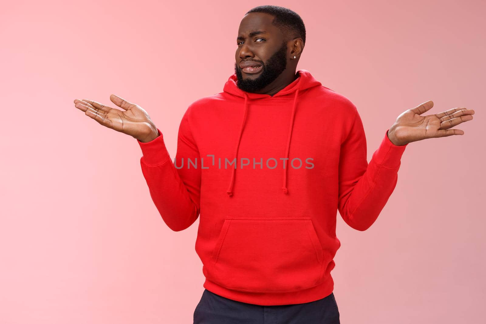 African american man cringe shake head unaware frowning grimacing aversion dislike shrugging hands raised sideways have no idea, standing dissatisfied unpleasant question, clueless pink background.