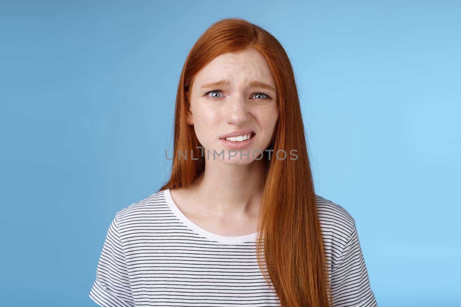 Displeased young awkward redhead girl cringe full disbelief smirking frowning confused look questioned doubtful hearing nuisance dumb story standing blue background uncertain by Benzoix