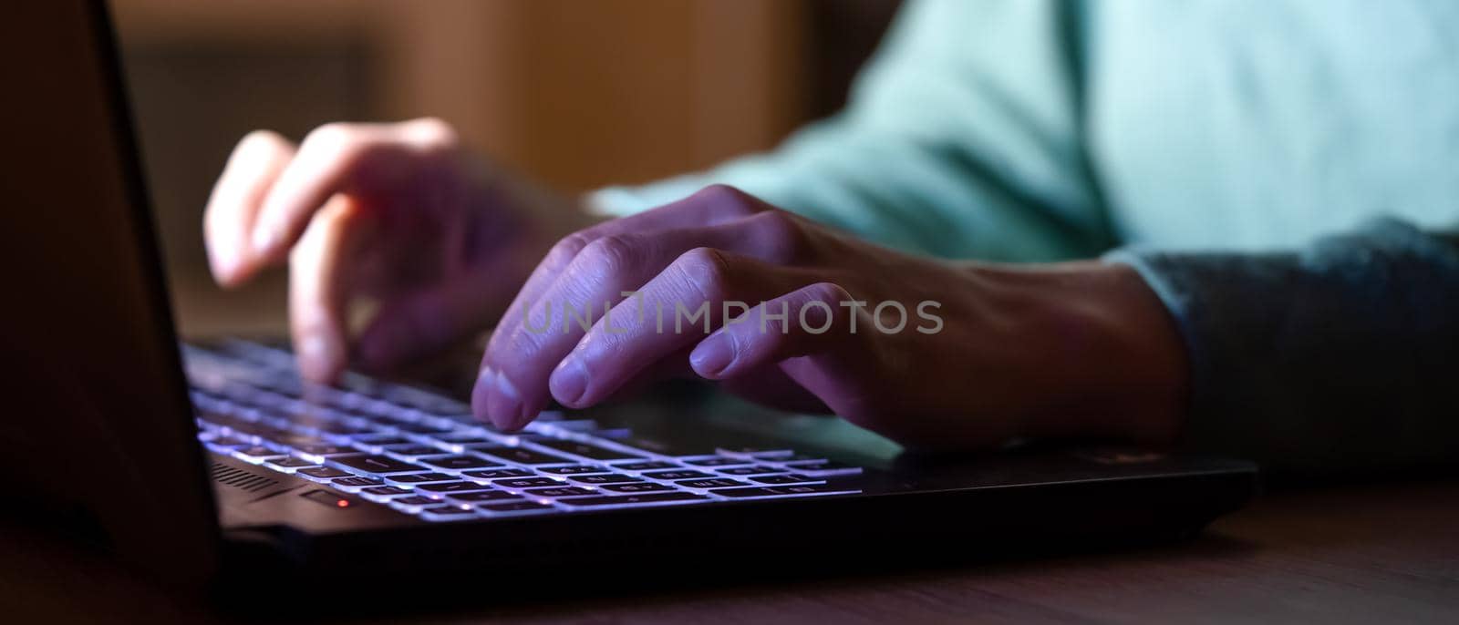 A girl works at a laptop at night online, texting, looking for information, studying, female hands on the keyboard close-up.