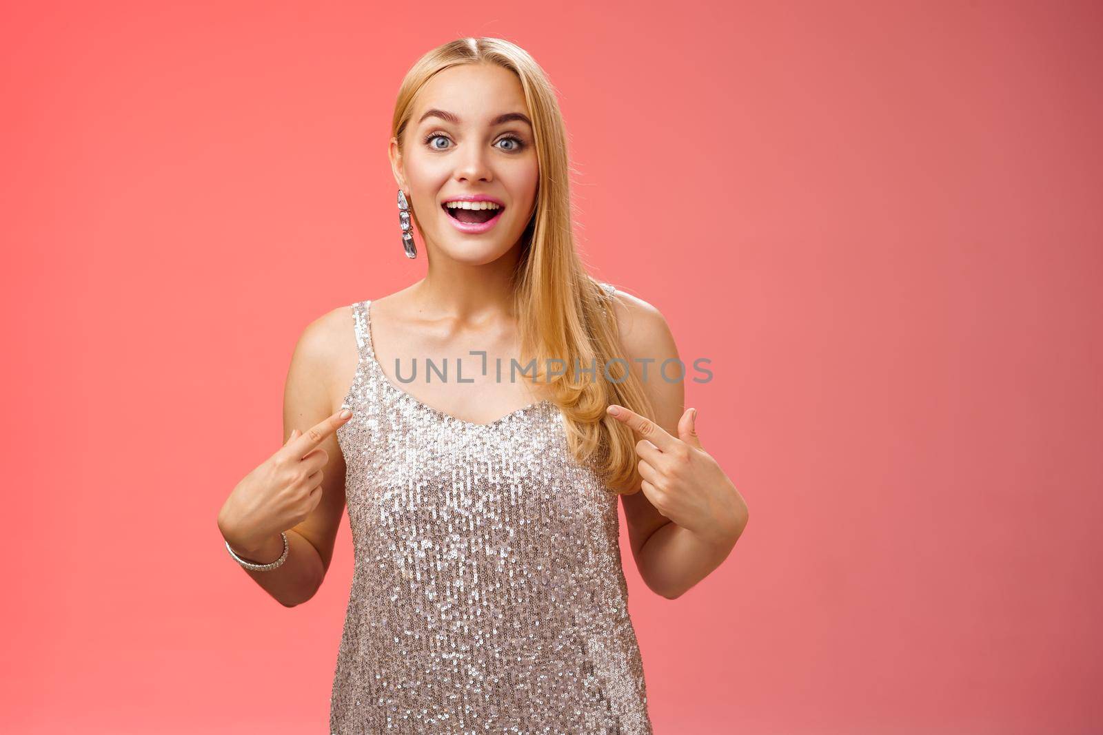 Surprised wondered happy blond charming cheerful woman in glittering silver dress pointing herself amused thrilled picked be chosen participate awesome event, standing joyful red background.