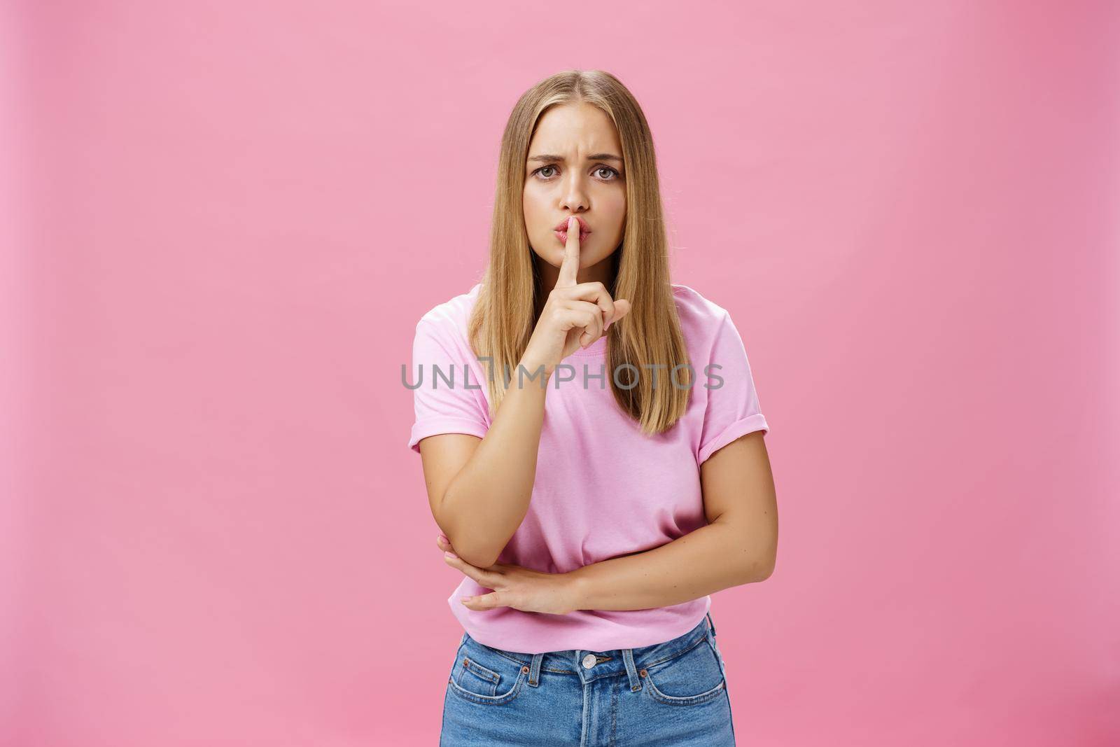 Shh keep voice down. Serious-looking concerned determined female nanny looking after kid asking not speak showing shush gesture with index finger over mouth, having secret concerned someone know it by Benzoix