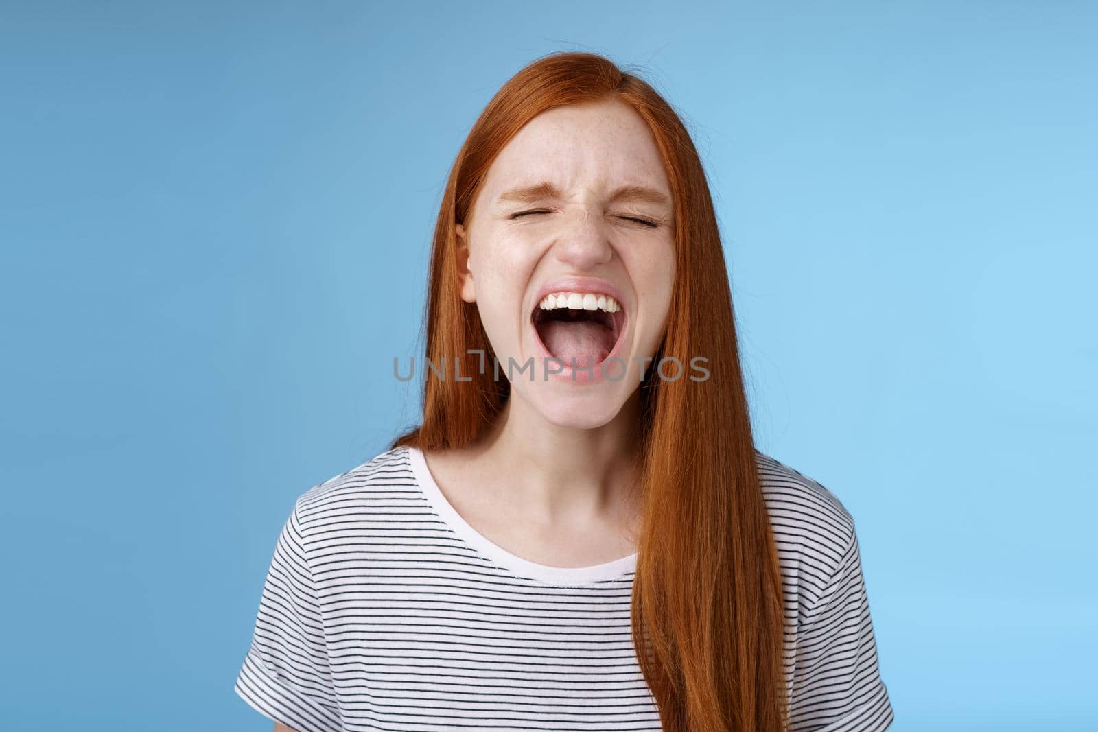 Girl screaming out loud showing attitude take out stress being fed up complaining hursh life shouting closed eyes yelling pissed standing bothered distressed blue background. Copy space