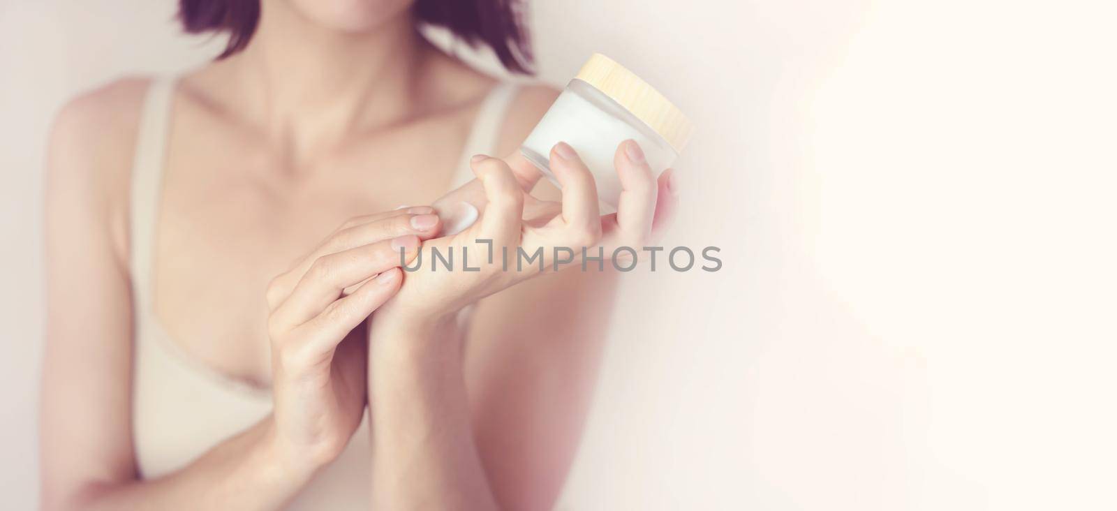Young female hands hold a jar of moisturizing cream to maintain health, softness of the skin, the woman takes care of her health and beauty.