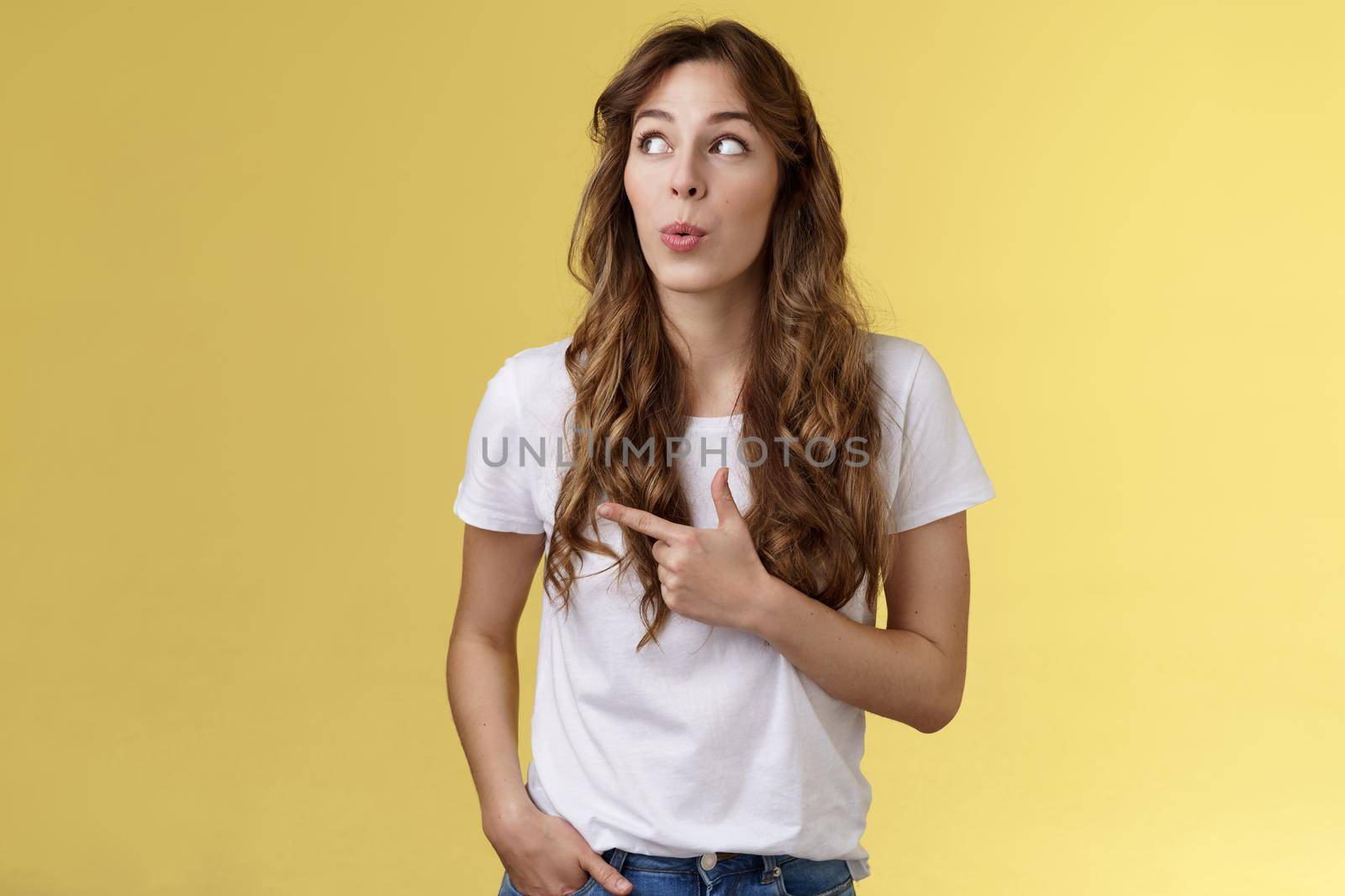 Hmm interesting wow. Curious silly cute pretty woman long curly hairstyle folding lips admiration tempting try out new menu look pointing upper left corner fascinated intrigued yellow background.