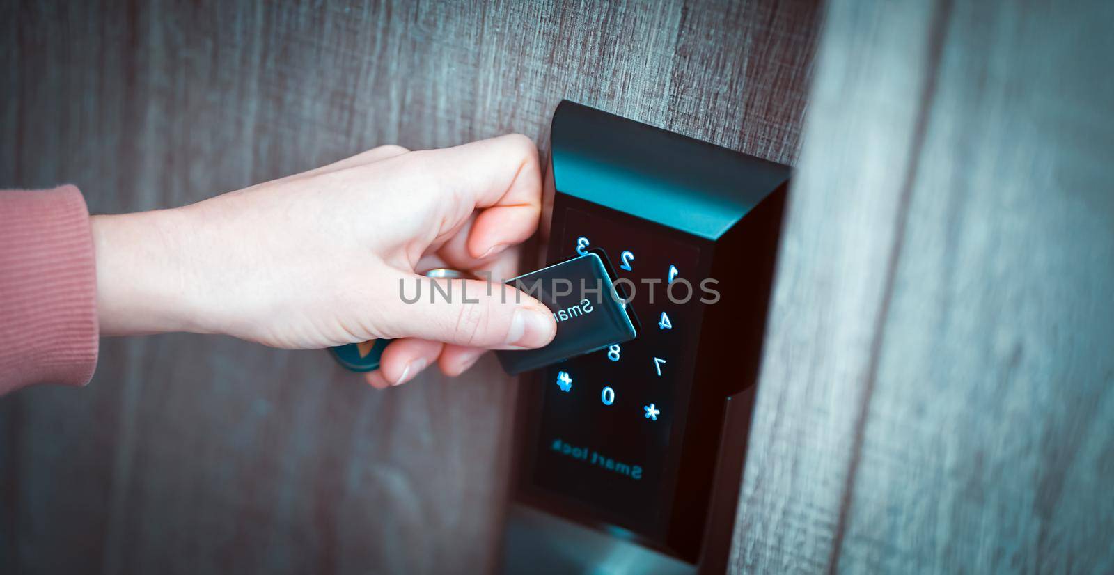 A woman's hand applies a card, opens the door of a house, apartment with a technological modern lock with a code, close-up view, home security.