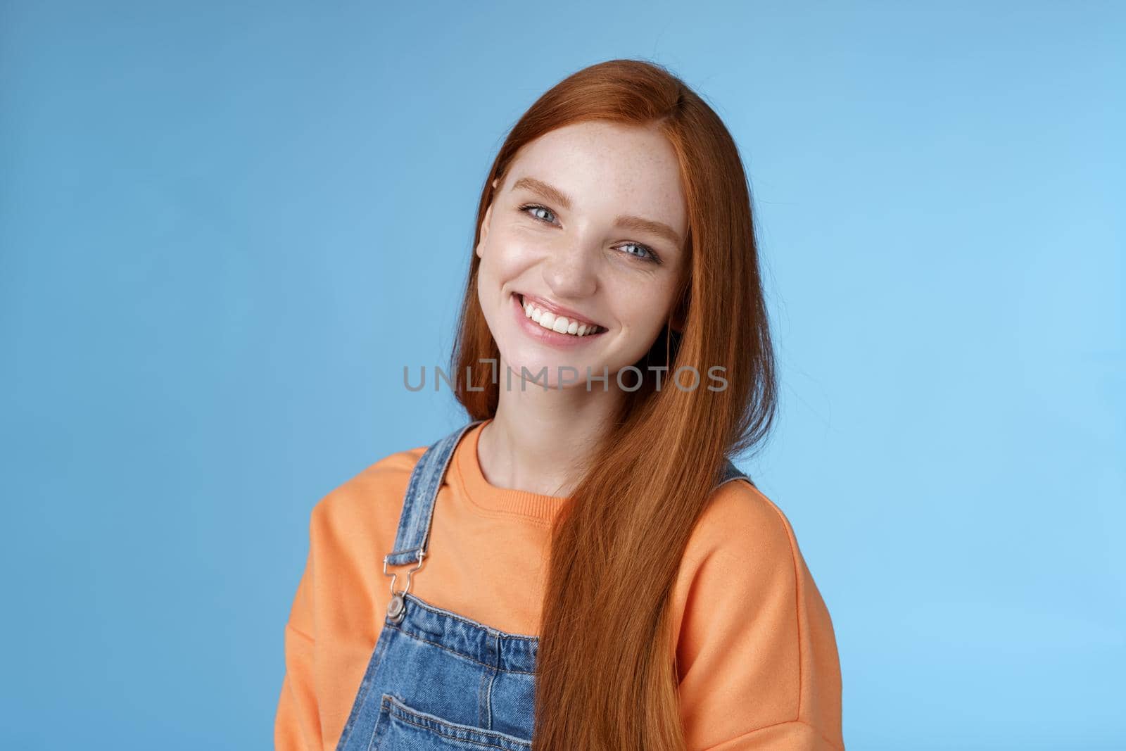 Pleasant sincere happy ginger girl blue eyes tilting head grinning happily laughing stay positive lucky spend time best friends receive praises compliments good job smiling delighted, blue background by Benzoix