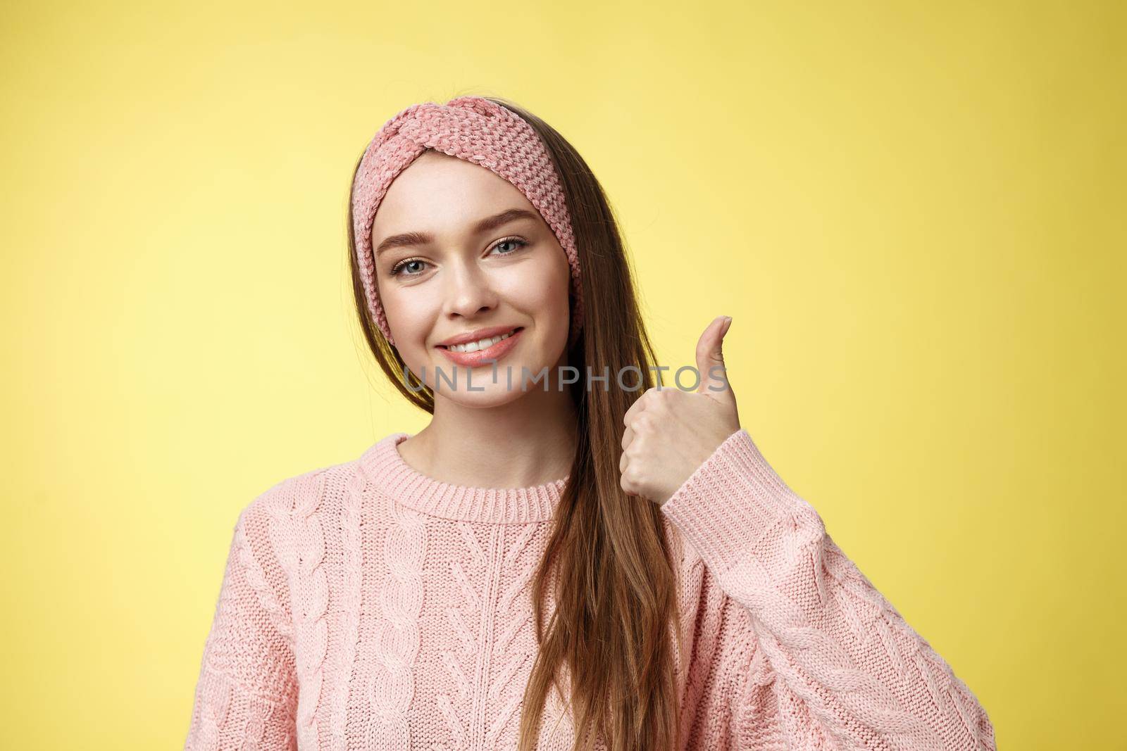 Pretty european young girl in headband, pink sweater smiling delighted, pleased showing thumbs up in agreement, approval, giving good recommendation, liking interesting great idea smiling cheerful by Benzoix