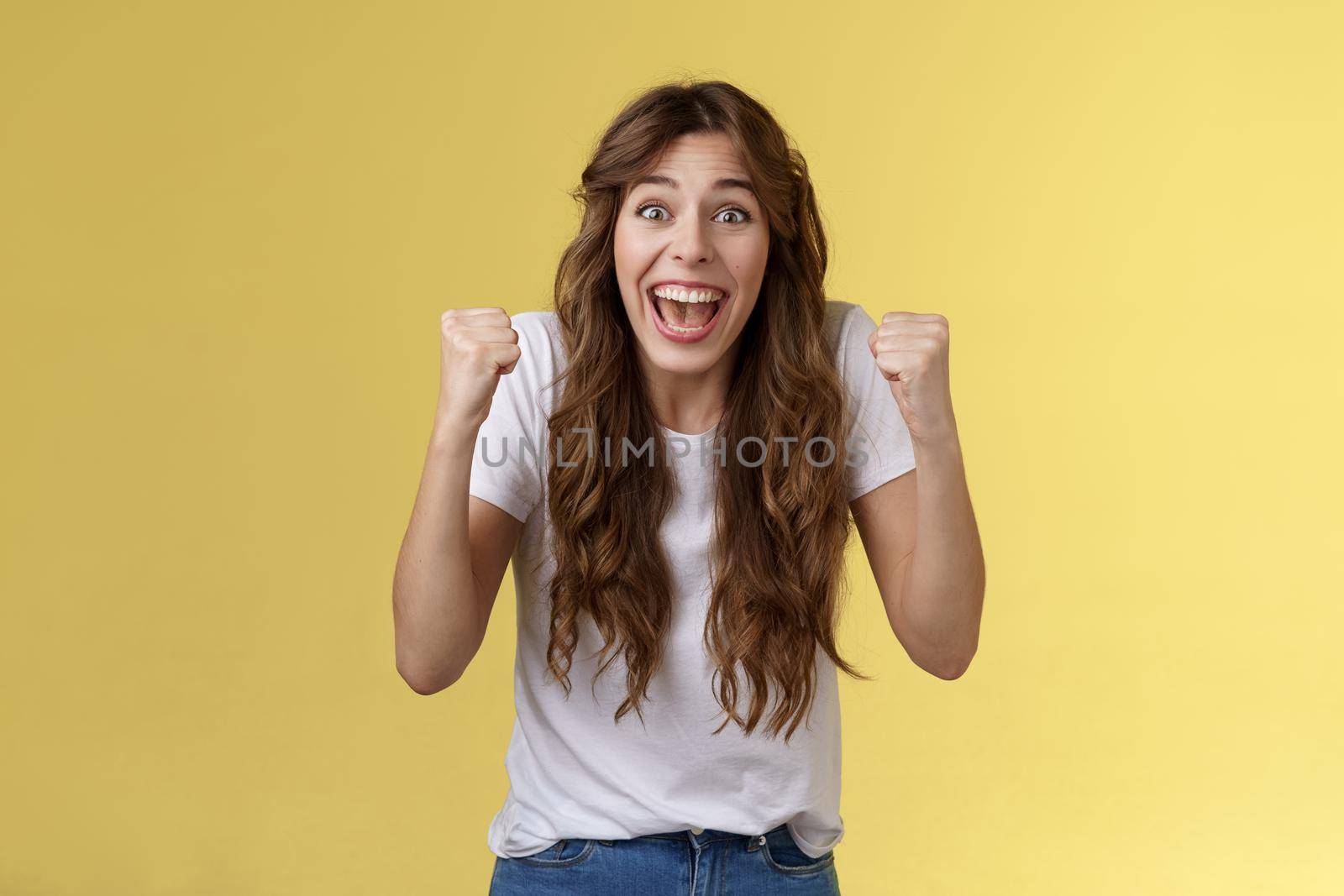 You can do it come on. Excited cheering supportive devoted fan rooting favorite team fist pump clench arms victory triumph gesture smiling broadly look camera excitement joy winning yellow background.