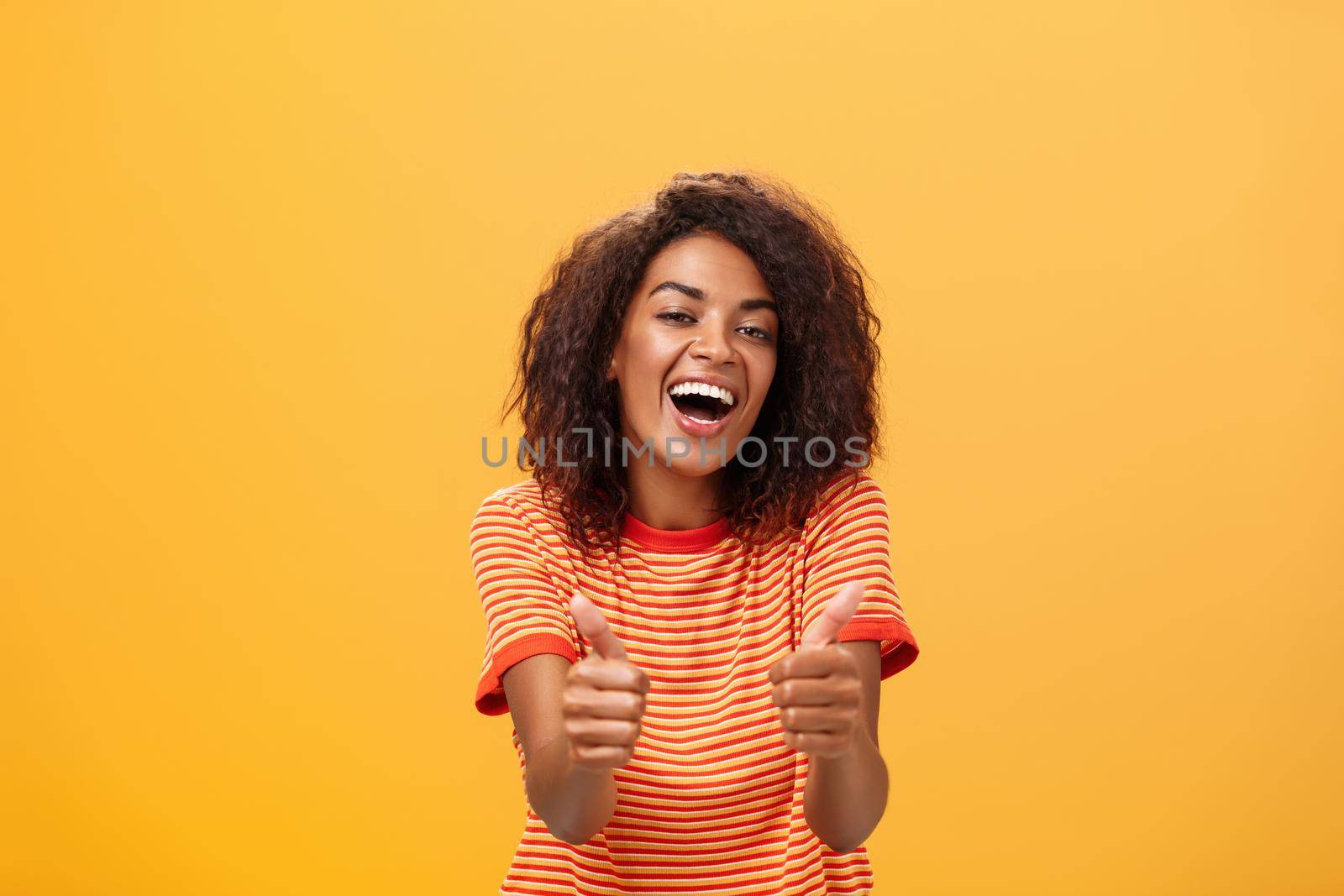 Woman surely knows how boost mood. Portrait of friendly-looking stylish and outgoing african american girlfriend with curly hairstyle showing thumbs up in like and approval agreeing to friend idea.