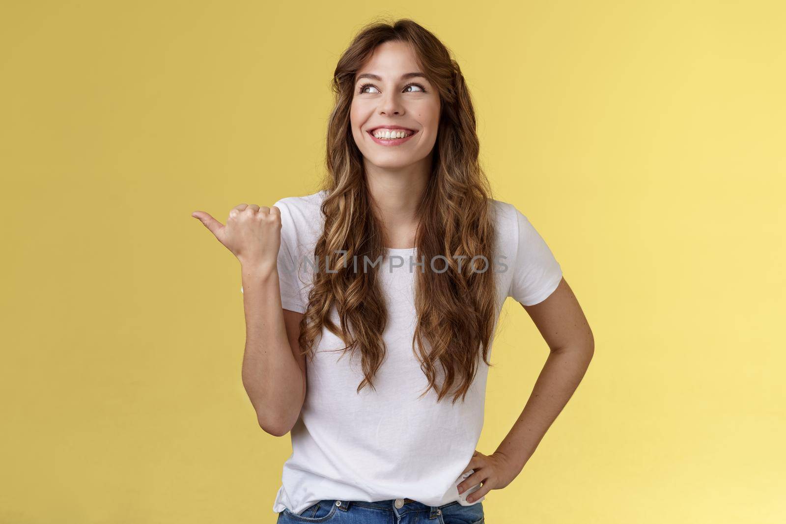 Satisfied carefree cheerful attractive european woman show thumb up pointing left turn aside pleased delighted expression discuss recent awesome purchase showing friend new car yellow background by Benzoix
