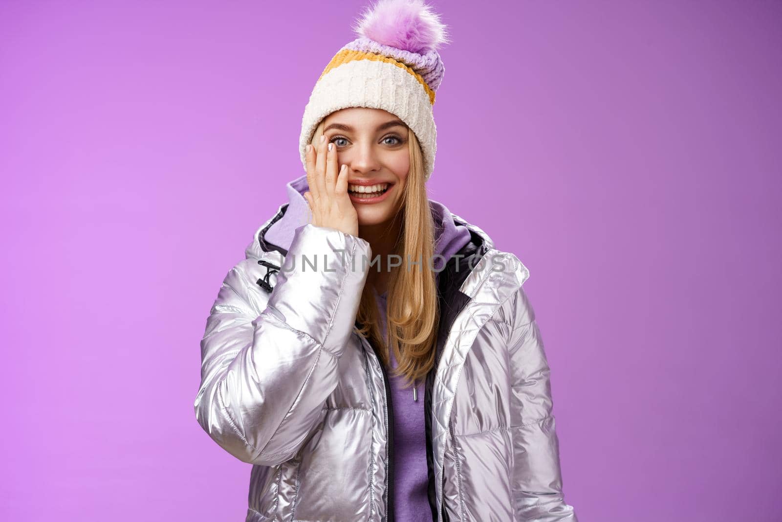 Delighted amused tender blond girlfriend fool around look playful playing snowballs touch cheek astonished feel dream come true enjoying vacation winter holidays boyfriend, standing purple background by Benzoix