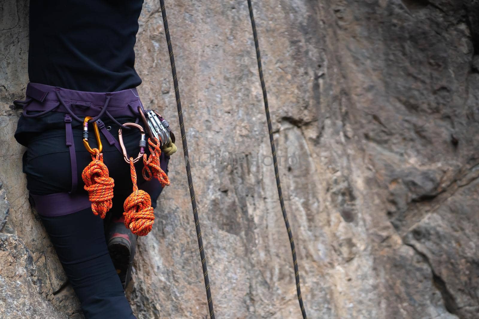 Climbing equipment, ropes, carabiners, harness, belay, close-up of a rock-climber put on by a girl, the traveler leads an active lifestyle and is engaged in mountaineering.