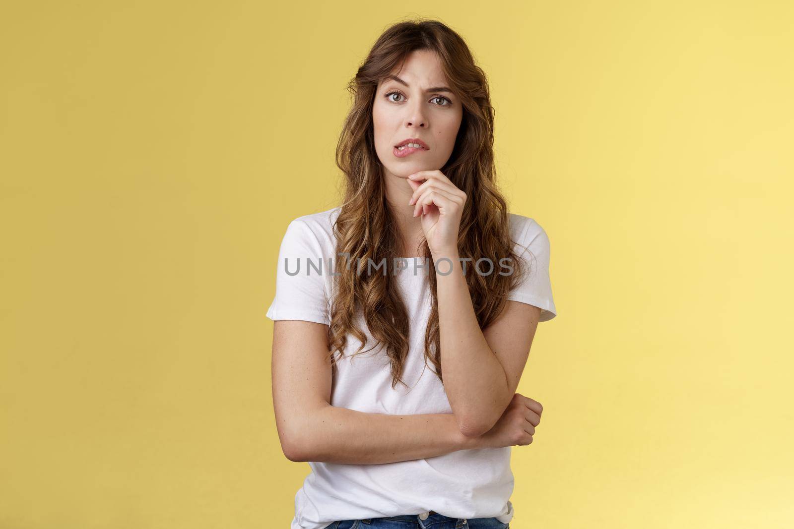 Troublesome situation give sec think. Intrigued thoughtful focused smart girlfriend thinking touch chin bite lip look camera focused pondering choice making decision solve problem yellow background.