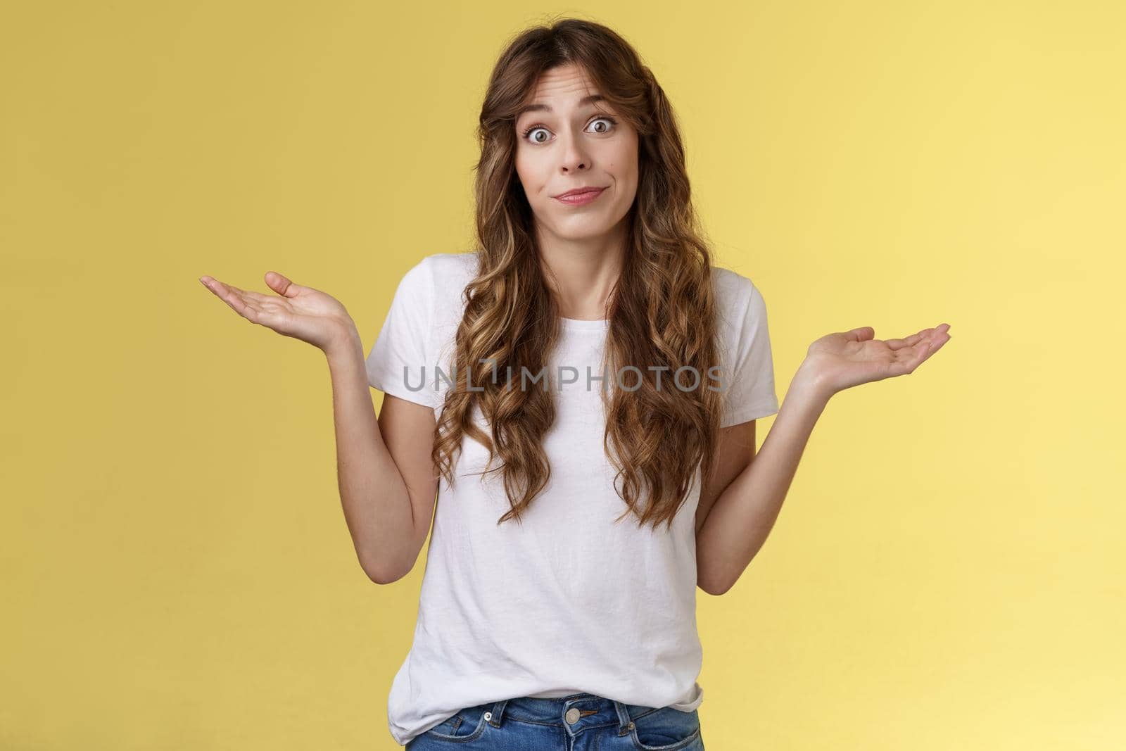 Sorry unable help. Clueless apathetic attractive female friend shrugging hands spread sideways full dibelief uncertain smirking unaware have no idea perplexed answer question yellow background.