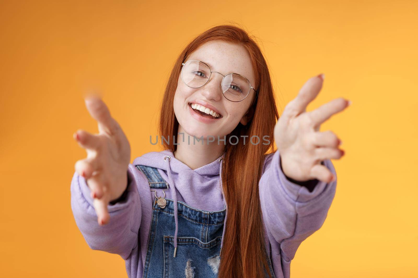 Come here let hold. Attractive silly friendly happy smiling redhead woman stretch arms camera grab product wanna tight friendship hugs grinning embracing cuddling besties, orange background.