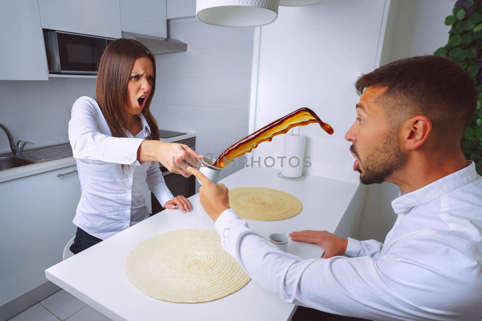 Young couple arguing at home. Relationship disagreements and problems. Angry woman throws coffee in mans face. High quality photo