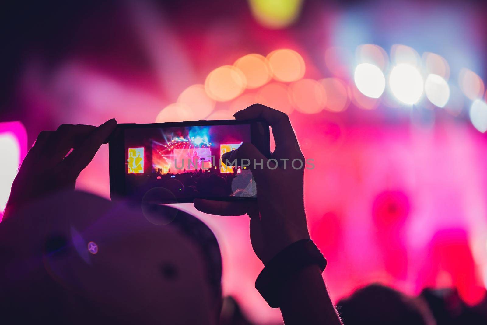 People enjoying rock concert and taking photos with cell phone at music festival by galitskaya
